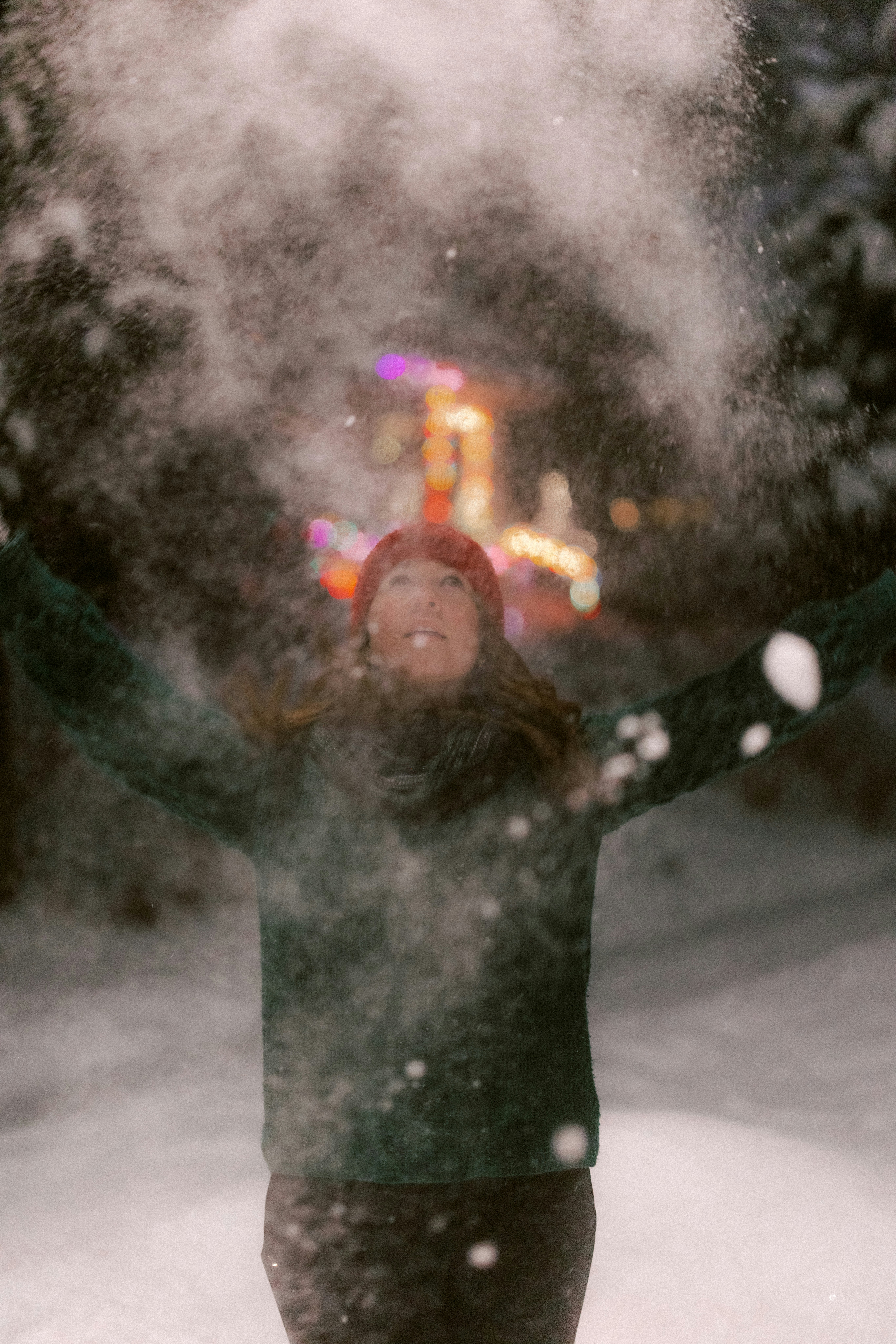 Woman throwing snow in the air at night