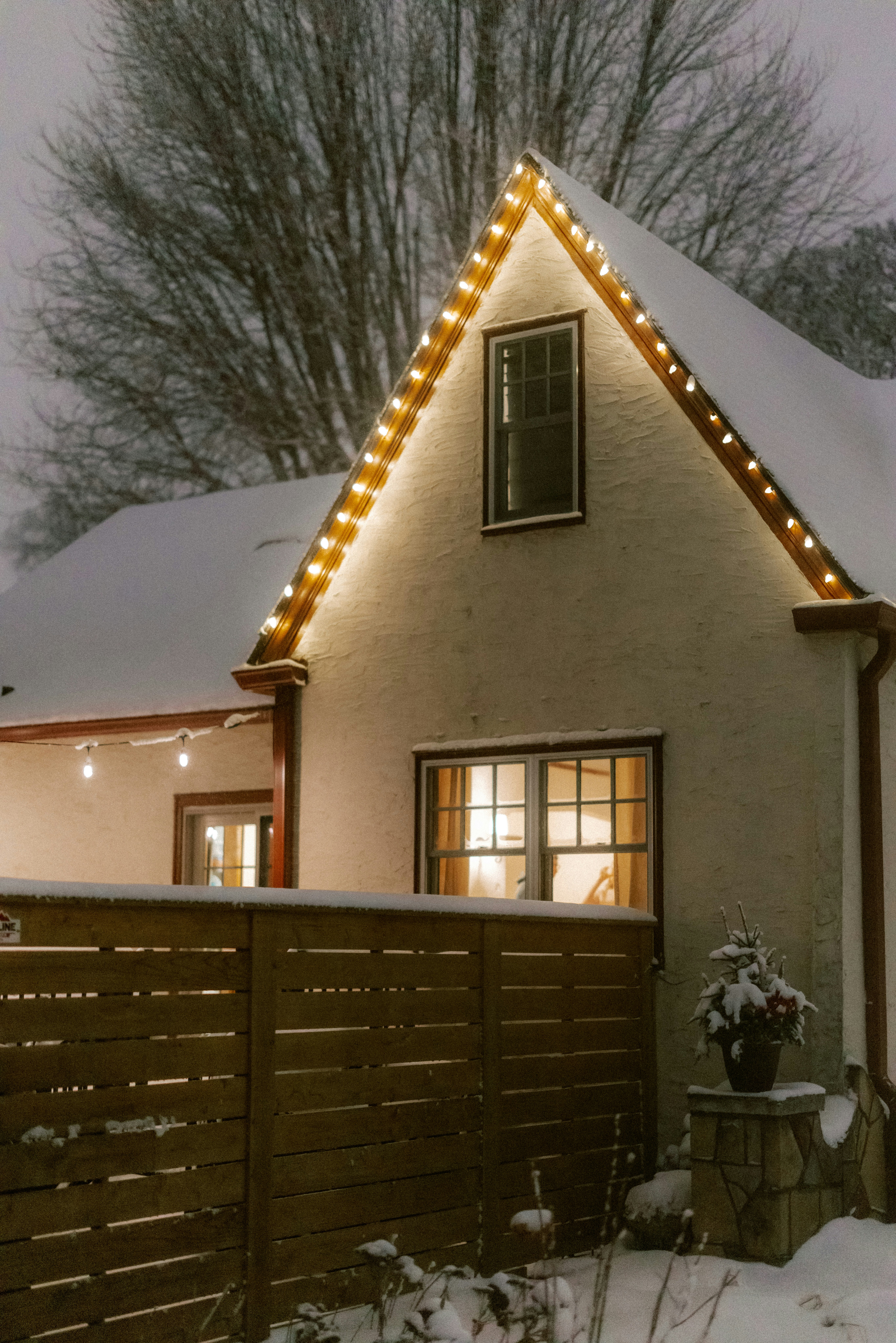 Ein Haus, das mit Weihnachtslichtern im Schnee geschmückt war.