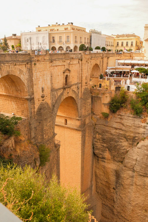 Historic stone bridge spanning a deep gorge with buildings.