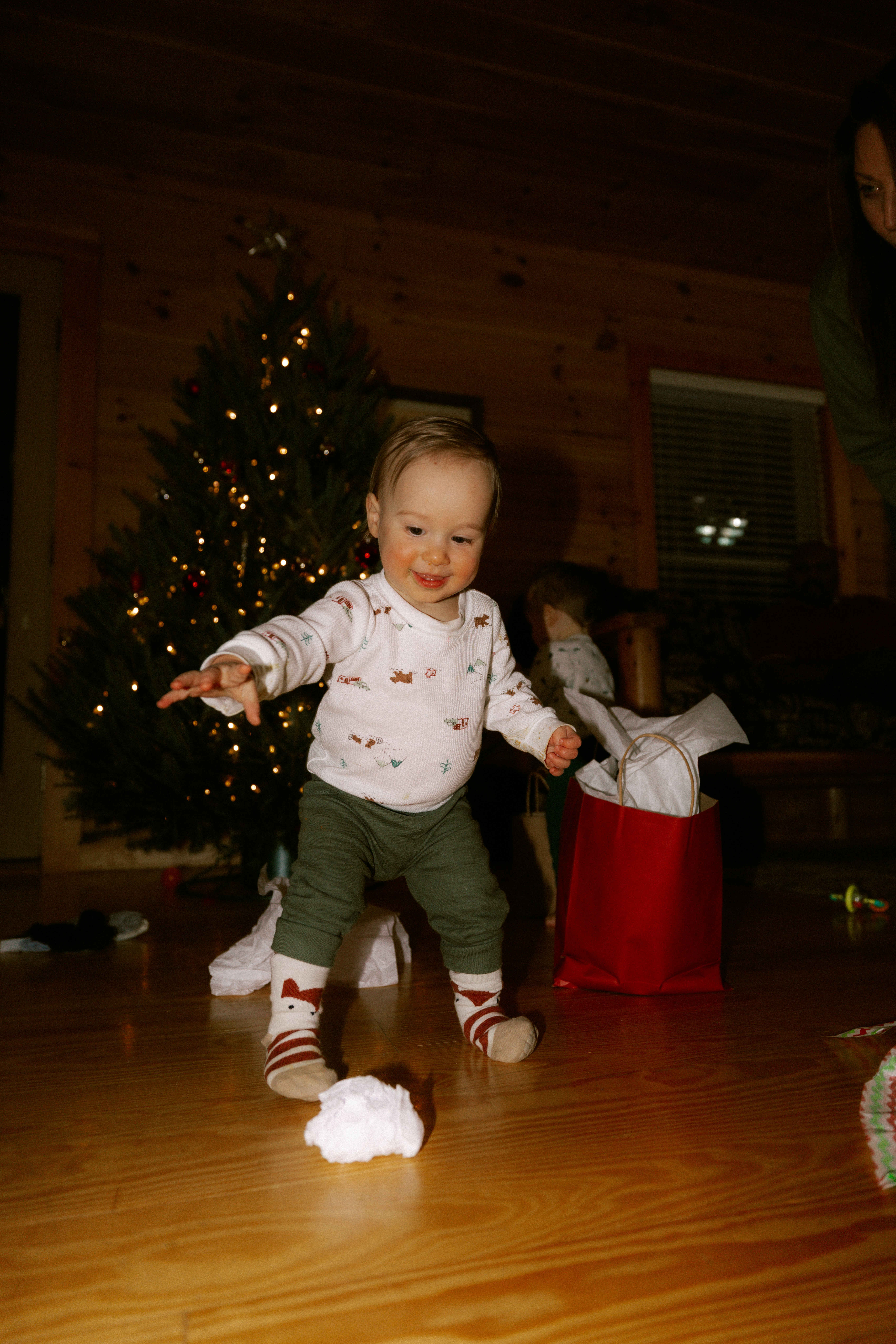Baby playing with a snowball near christmas tree