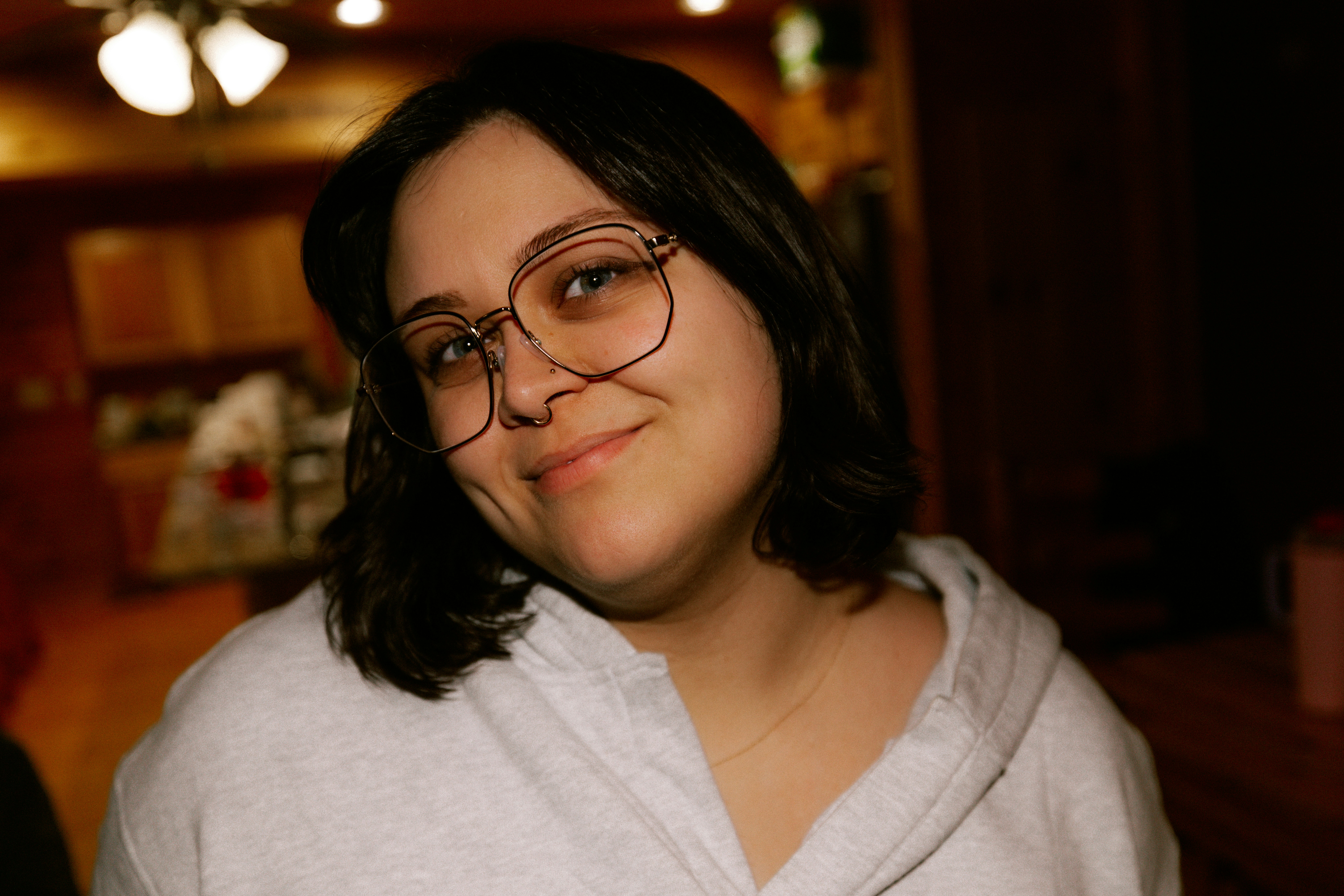 Junge Frau mit Brille lächelt drinnen