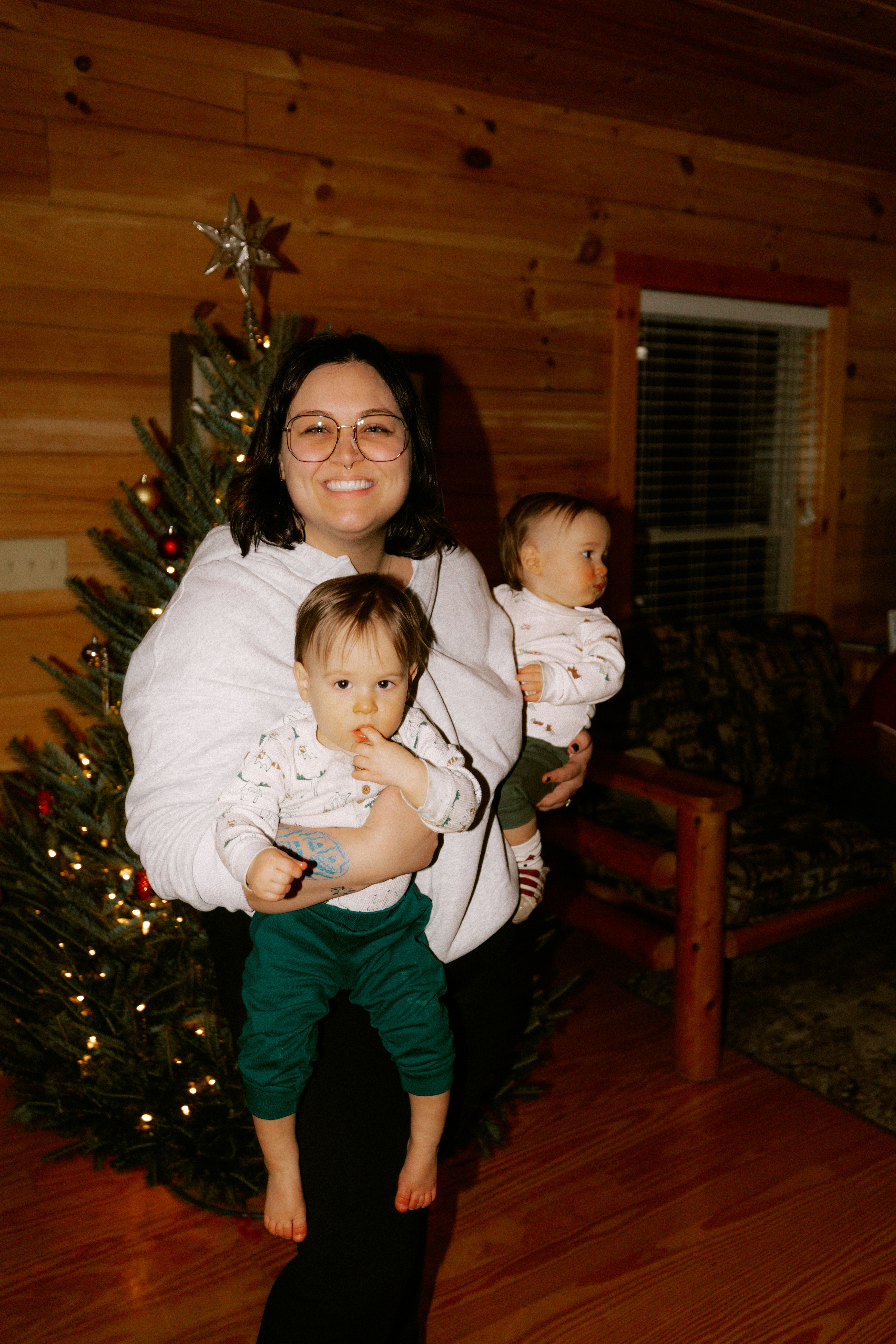 Woman holding two babies by a christmas tree