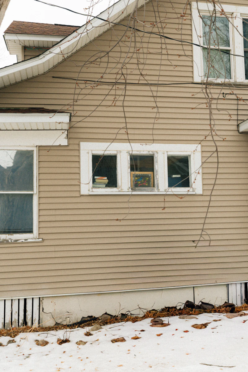 House front with siding, white trim around windows, and eaves