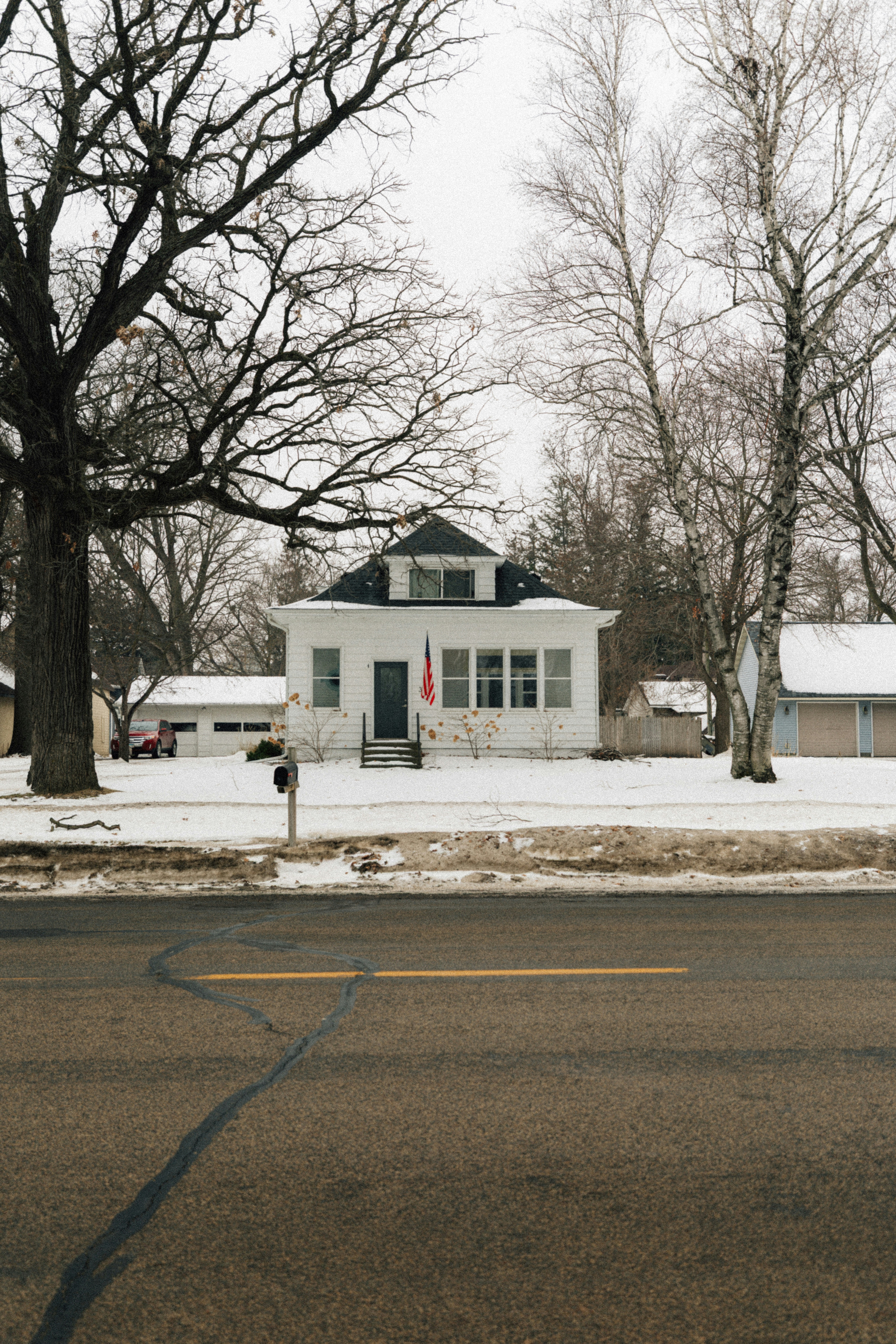 Ein weißes Haus in einer verschneiten Straße mit Bäumen.