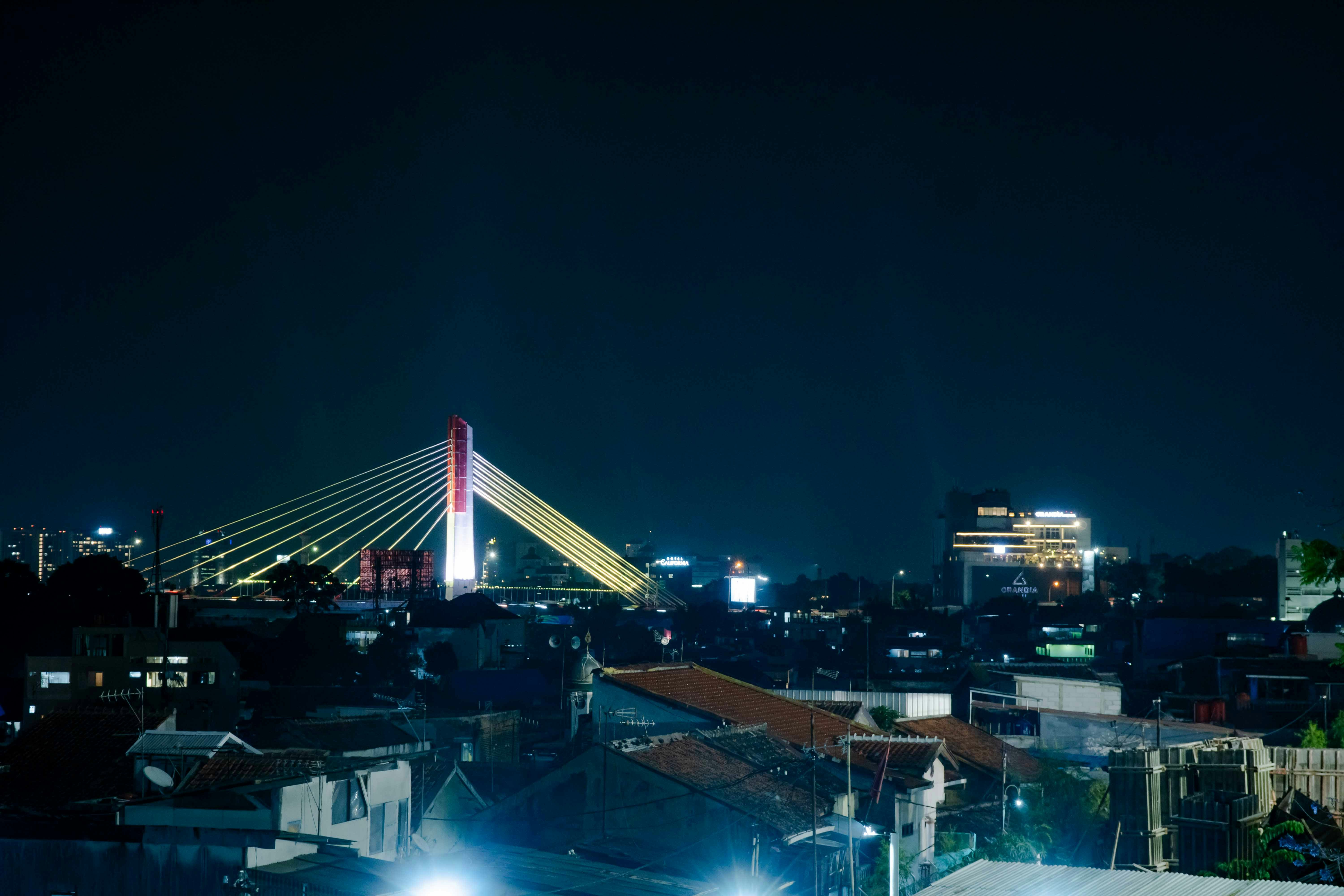 Illuminated bridge over a city skyline at night.