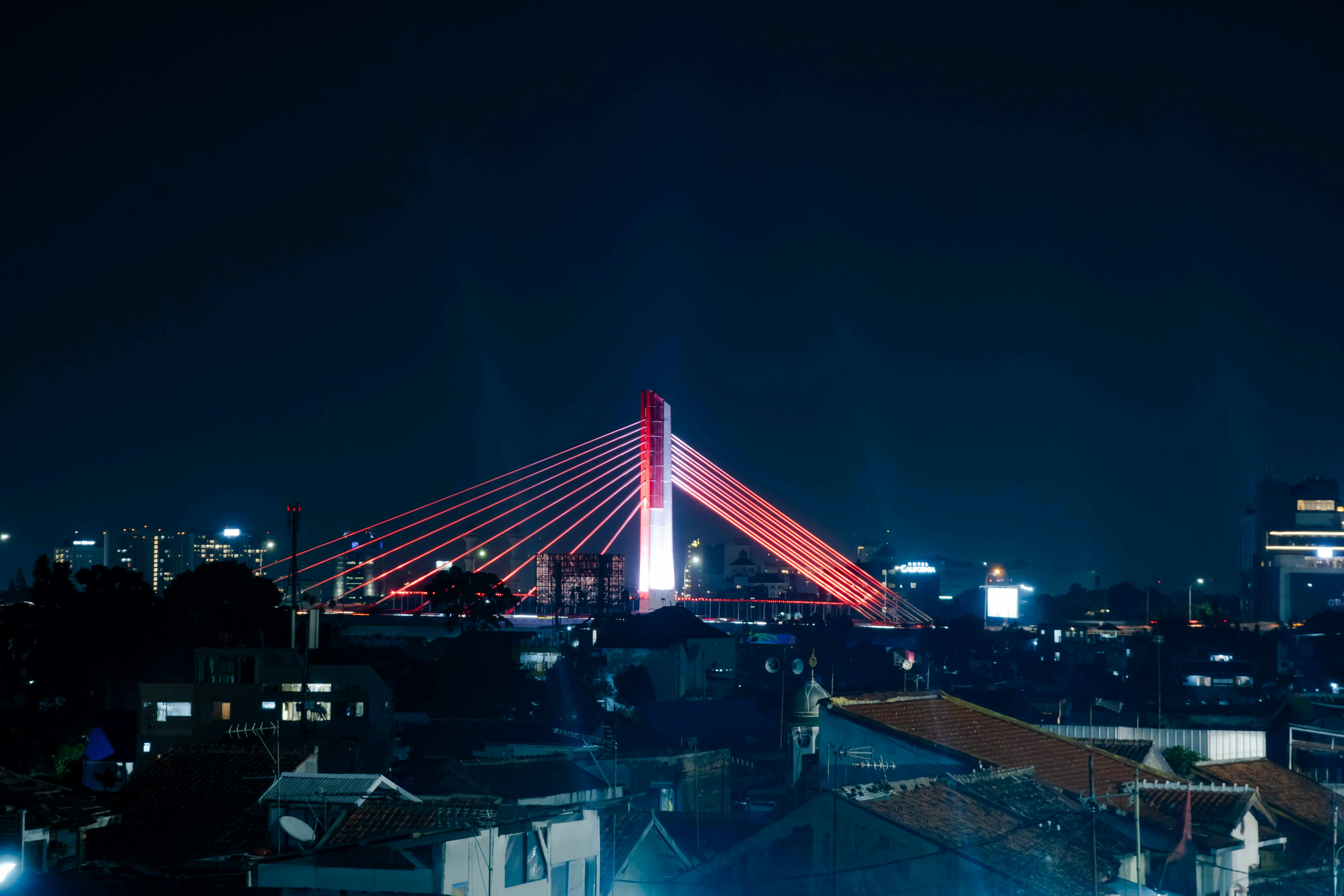 Illuminated bridge glowing red at night over cityscape