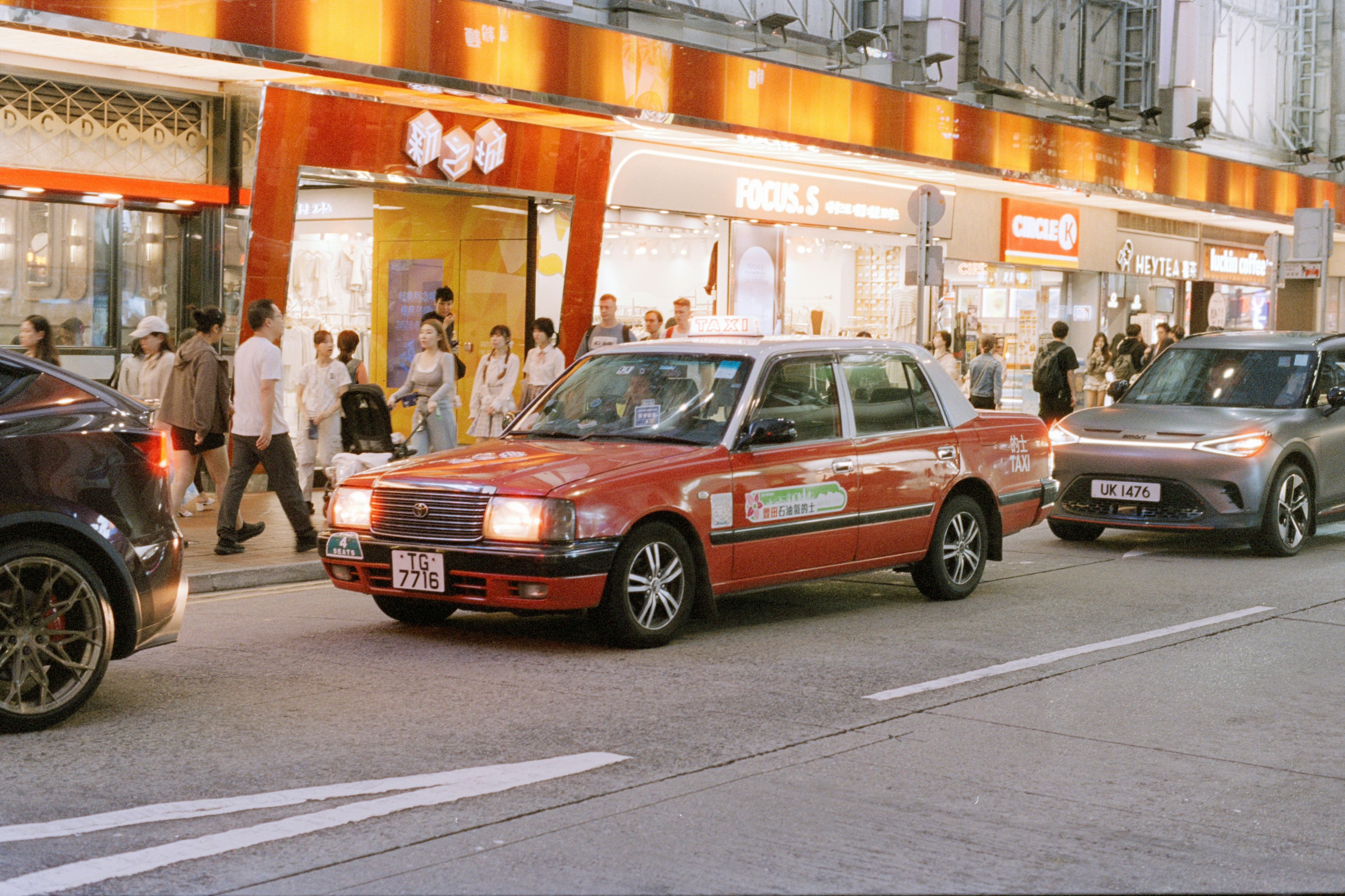 Red taxi drives down a busy city street.