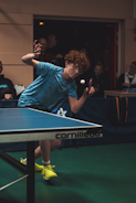 Teenager playing table tennis with intense focus.