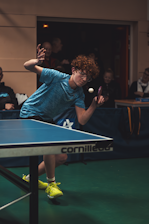 Teenager playing table tennis with intense focus.