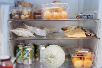Various foods and drinks stocked inside an open refrigerator