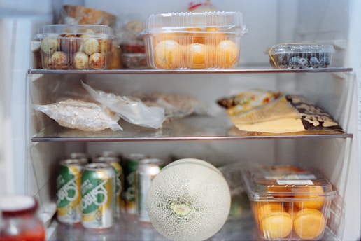 Various foods and drinks stocked inside an open refrigerator.