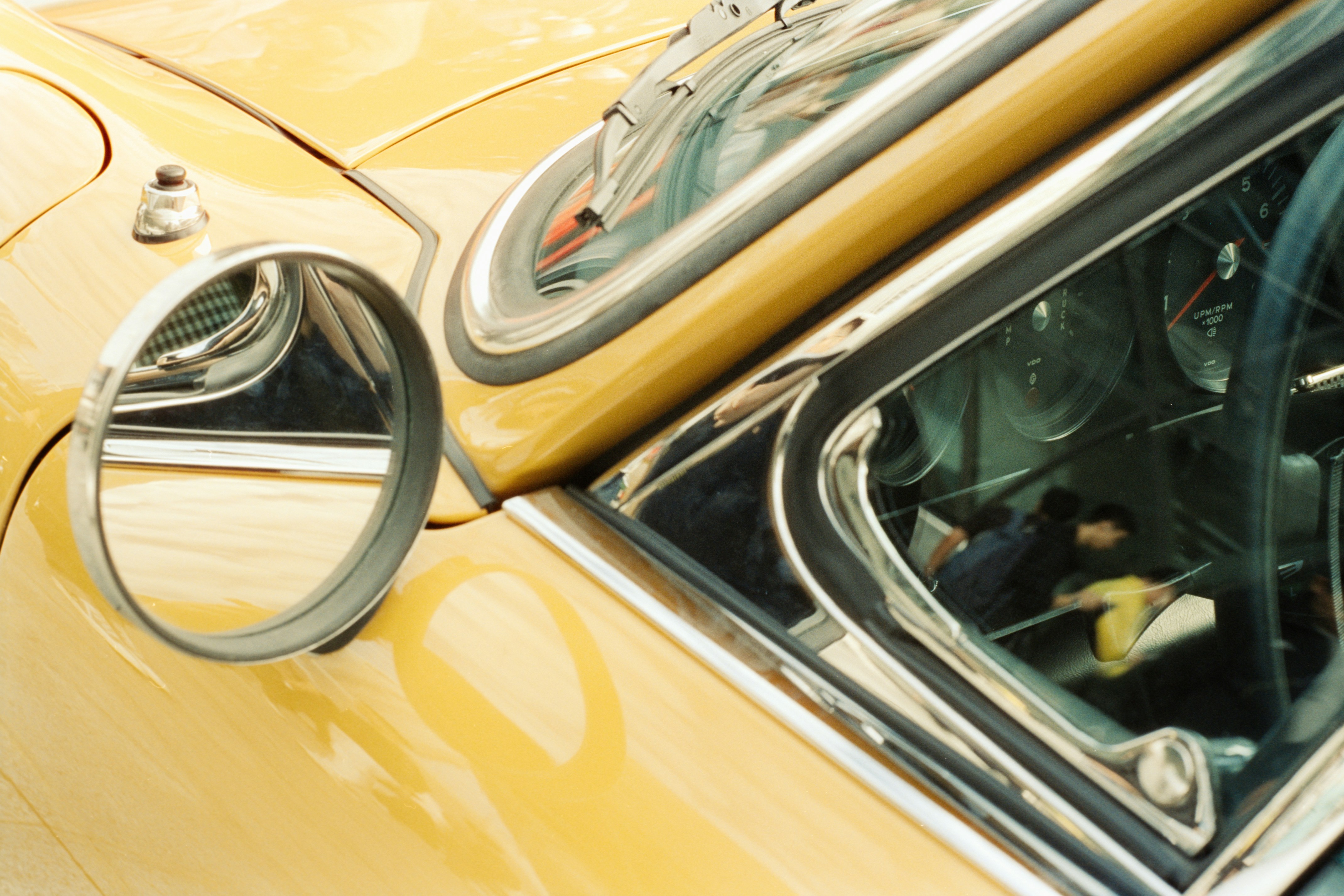 Close-up of a yellow vintage car's side mirror.