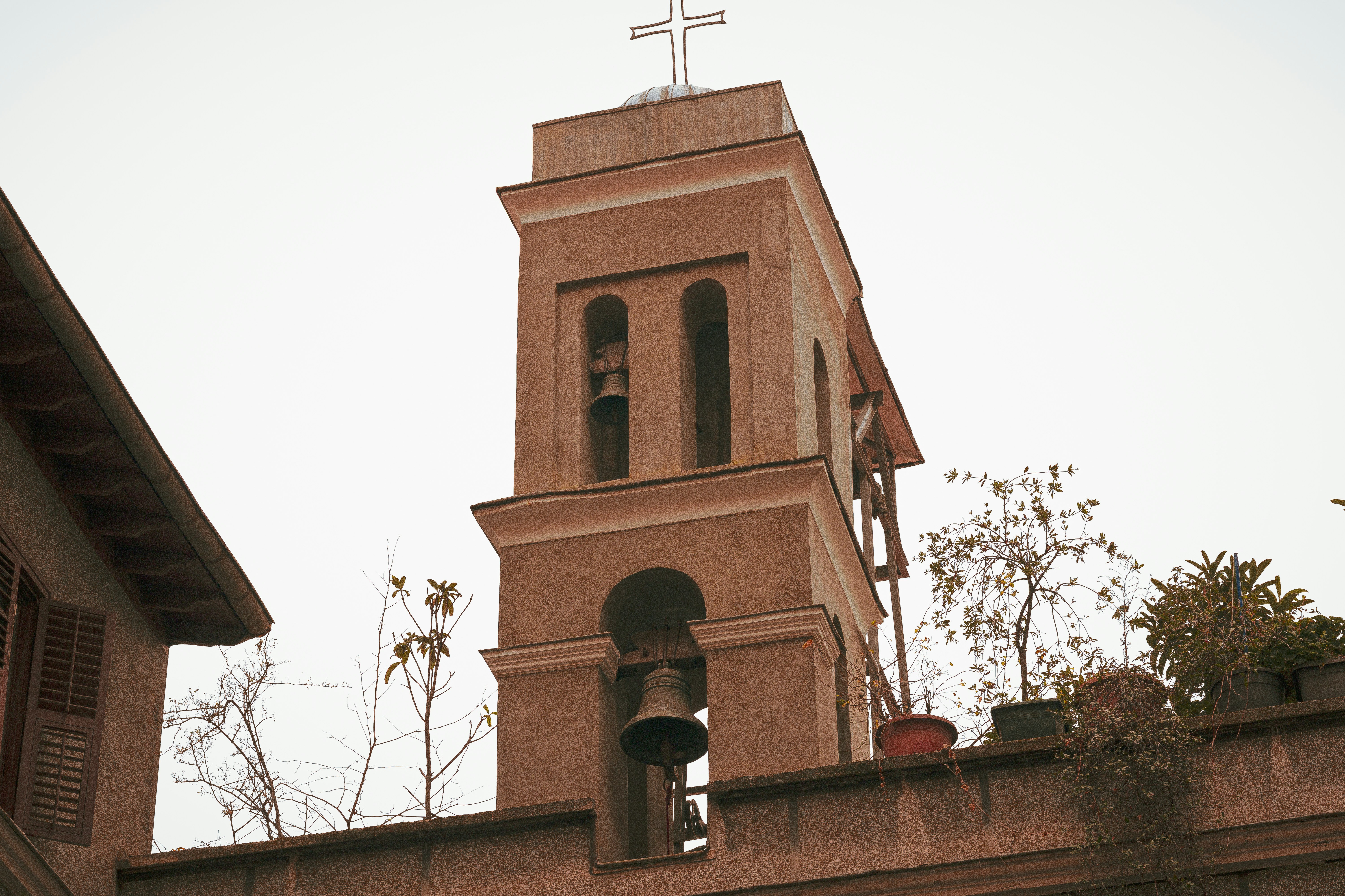 Bell tower with crosses and bells against a cloudy sky.