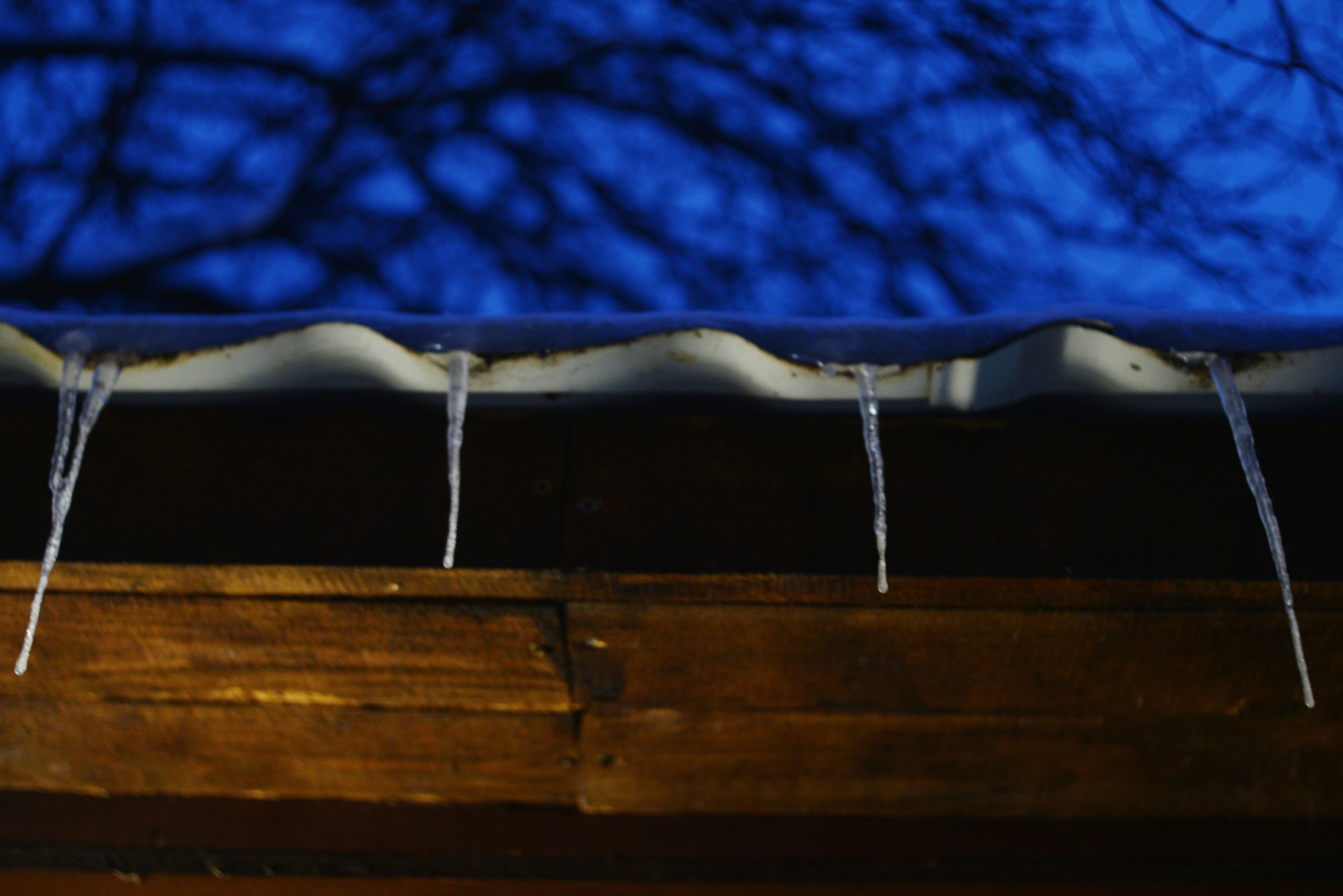 Large icicles hanging from a roof edge - Ice dam removal Boston