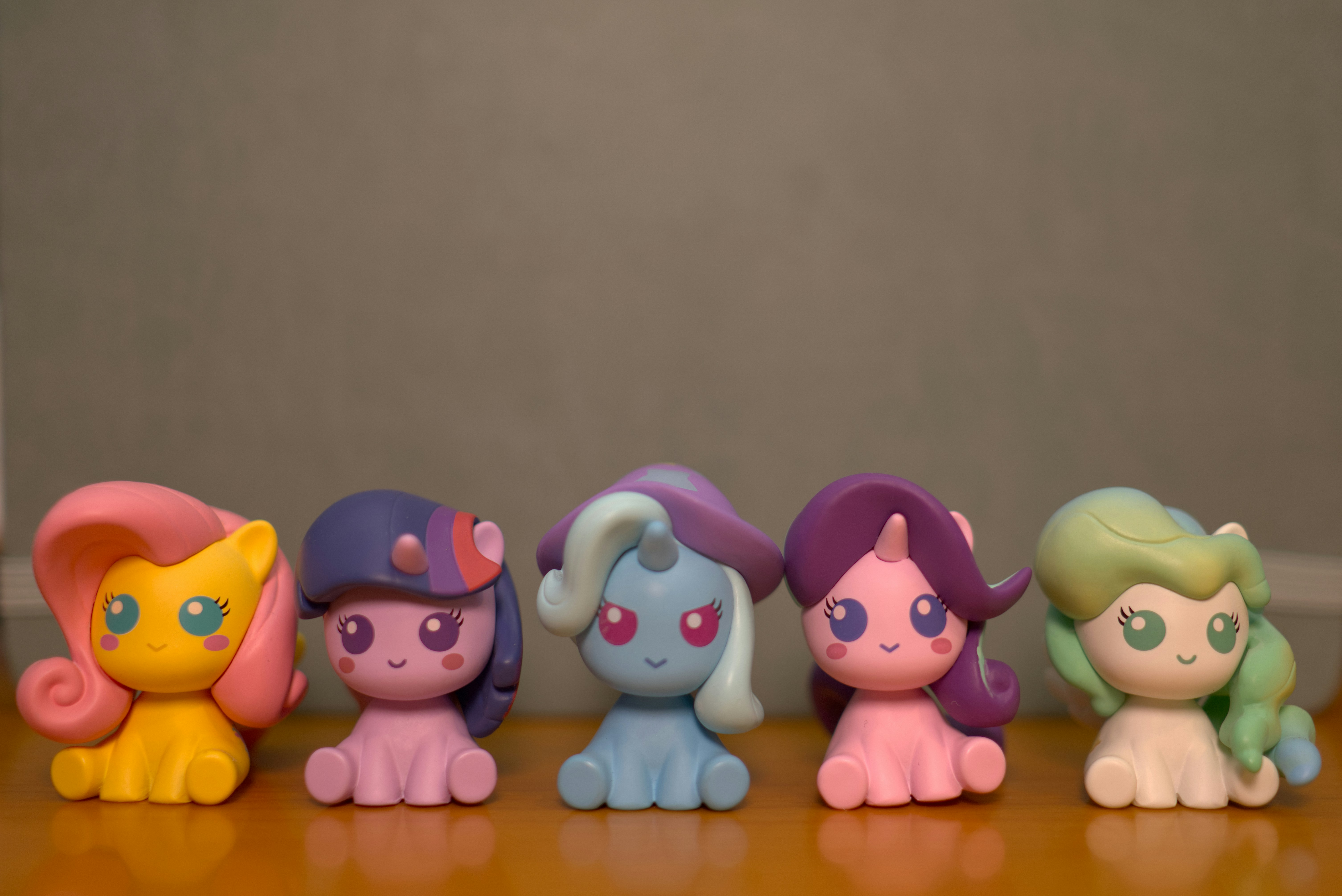 Five small cartoon ponies sitting in a row.