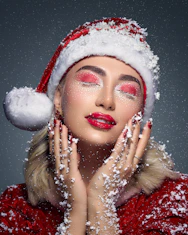 Woman in santa hat with festive makeup and snow