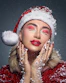 Woman in santa hat with festive makeup and snow