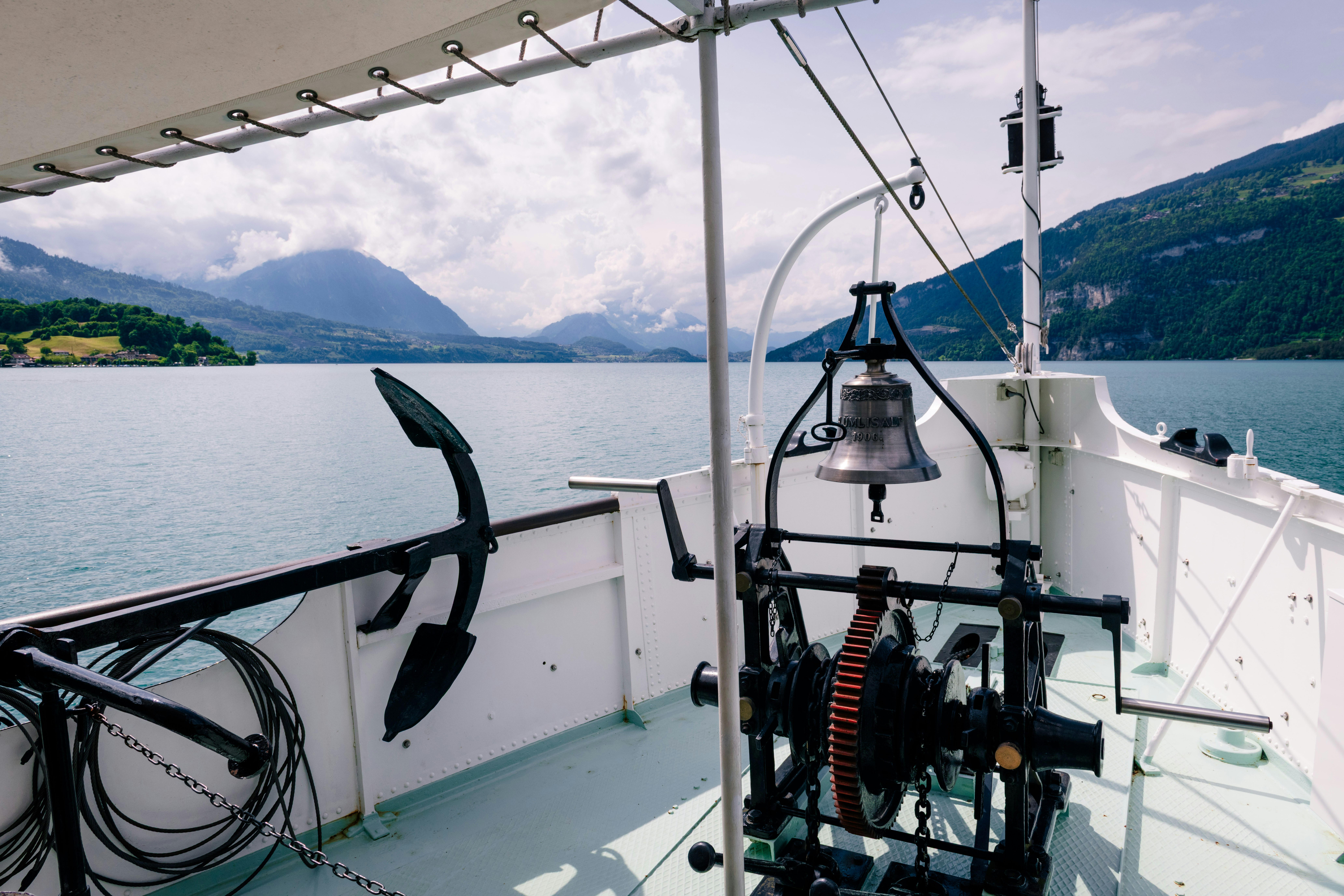 Bell and anchor on a boat with lake and mountains.