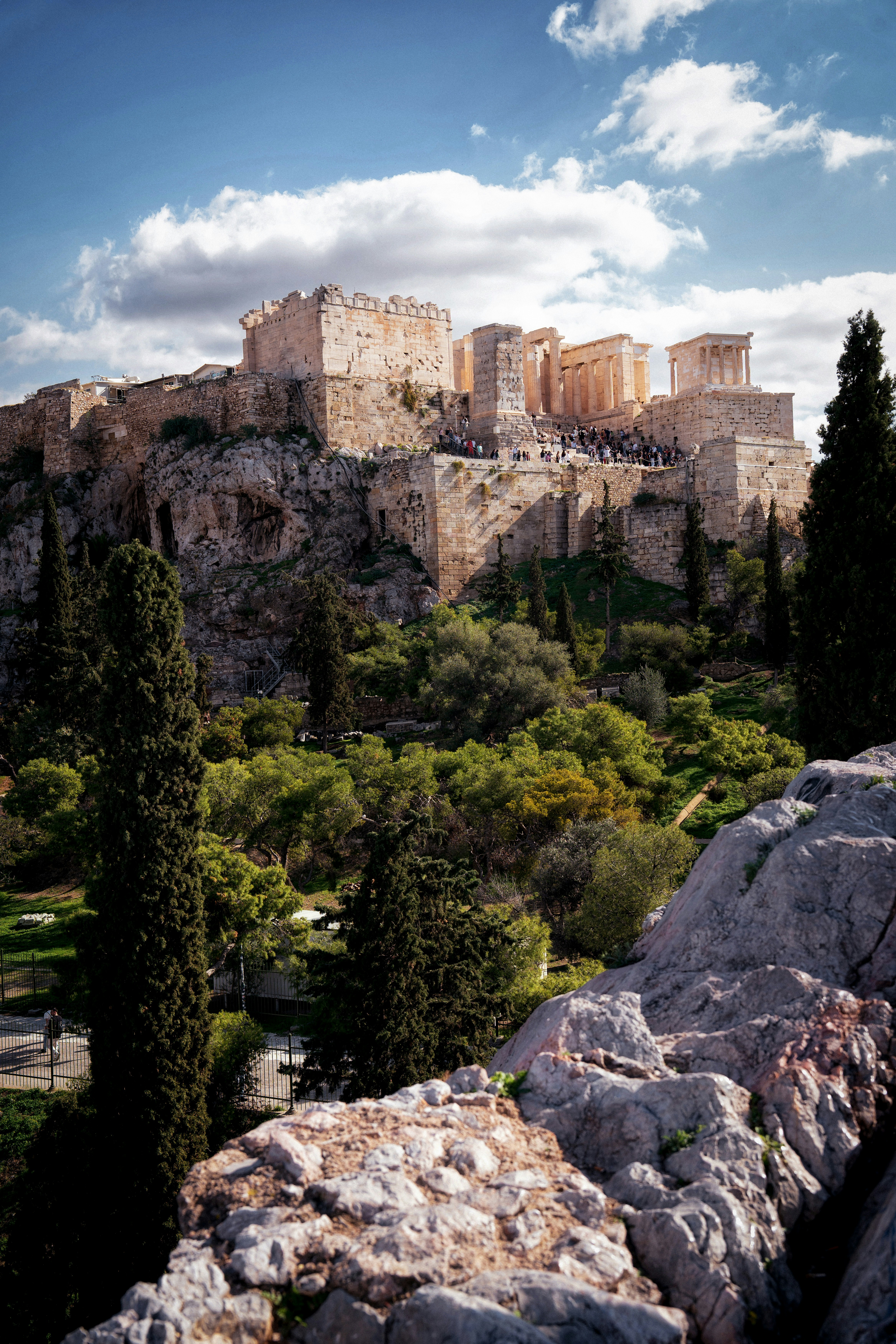 Ancient ruins atop a rocky hill under a cloudy sky.