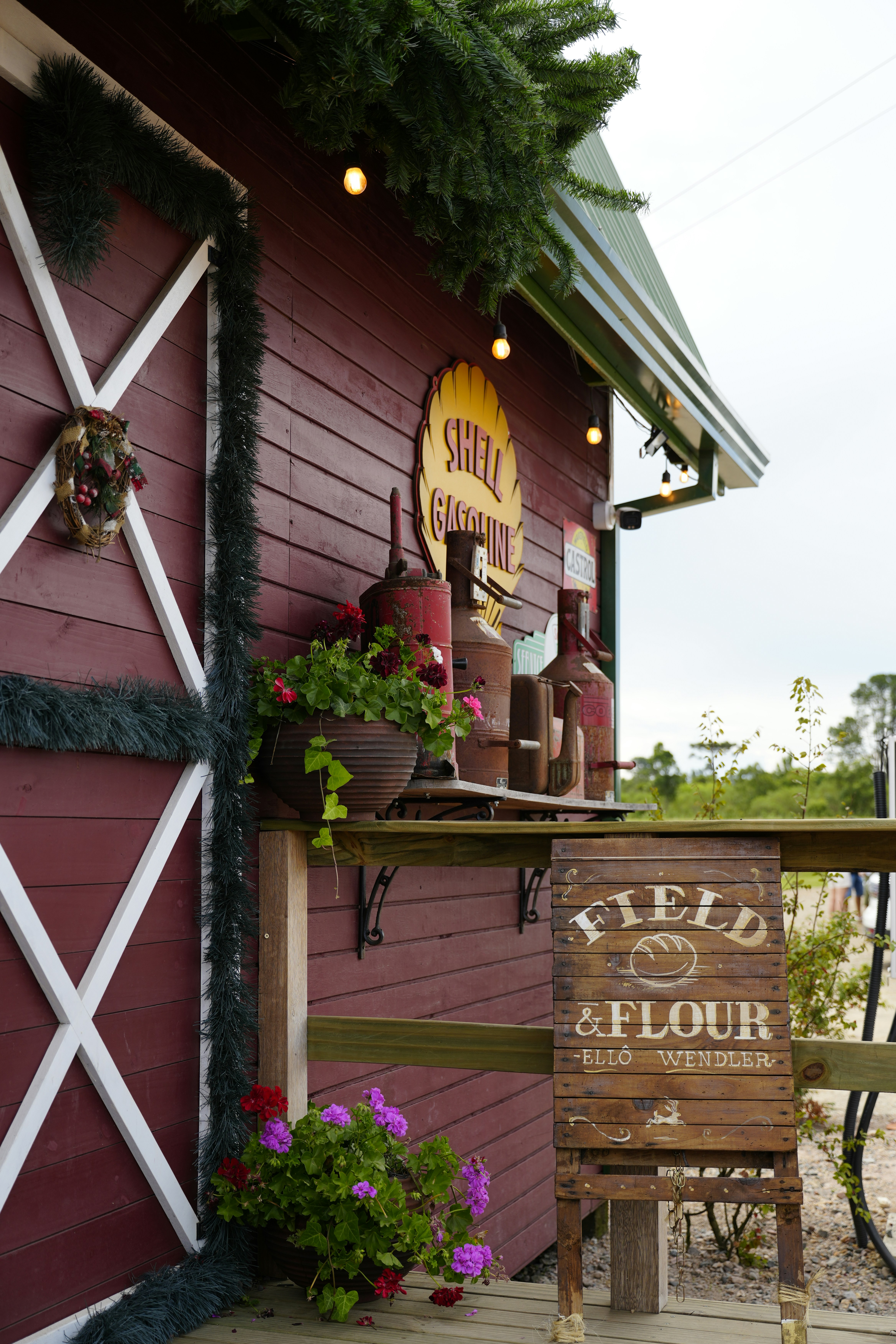 Red barn with "field & flour" sign and flowers.
