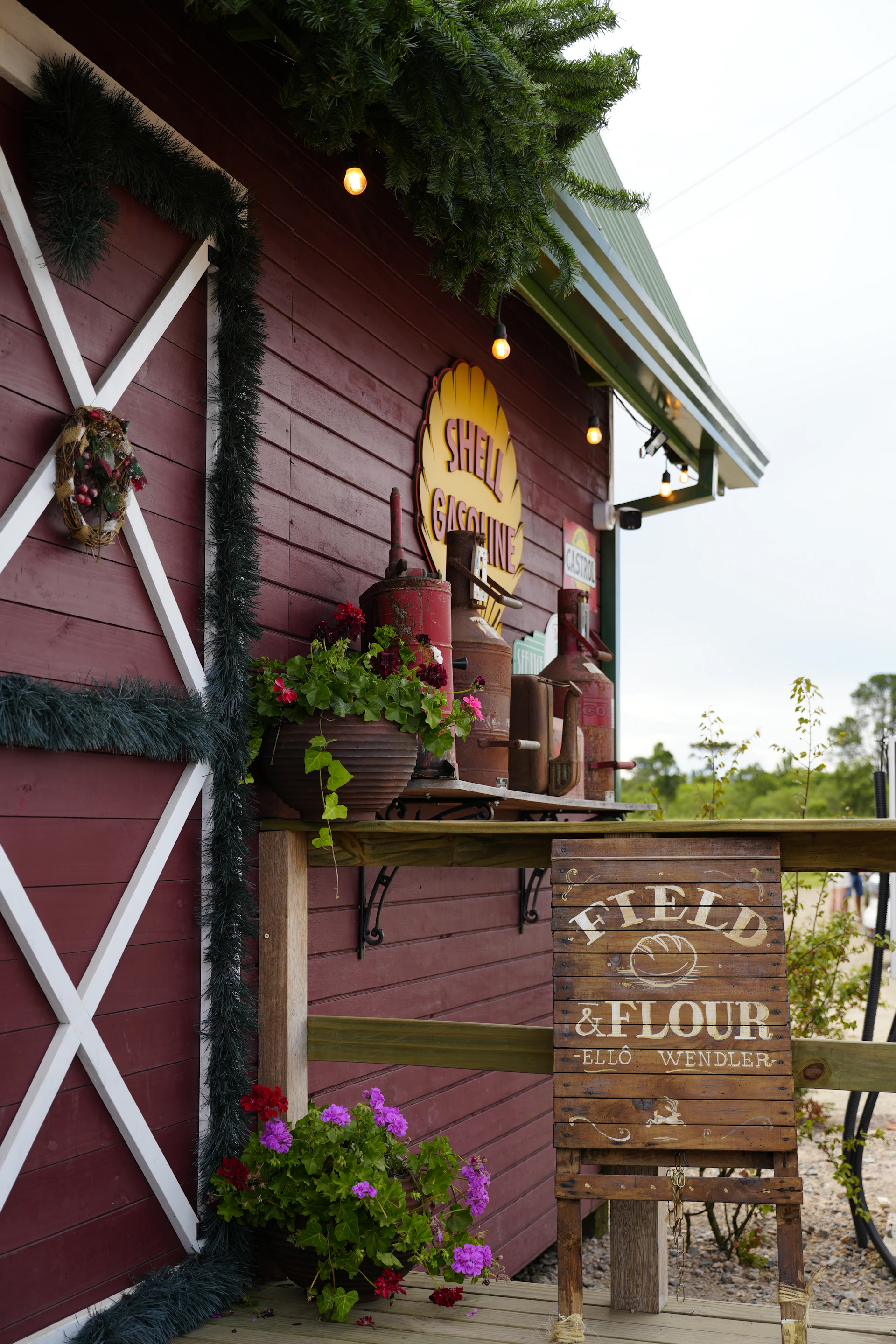 Red barn with "field & flour" sign and flowers