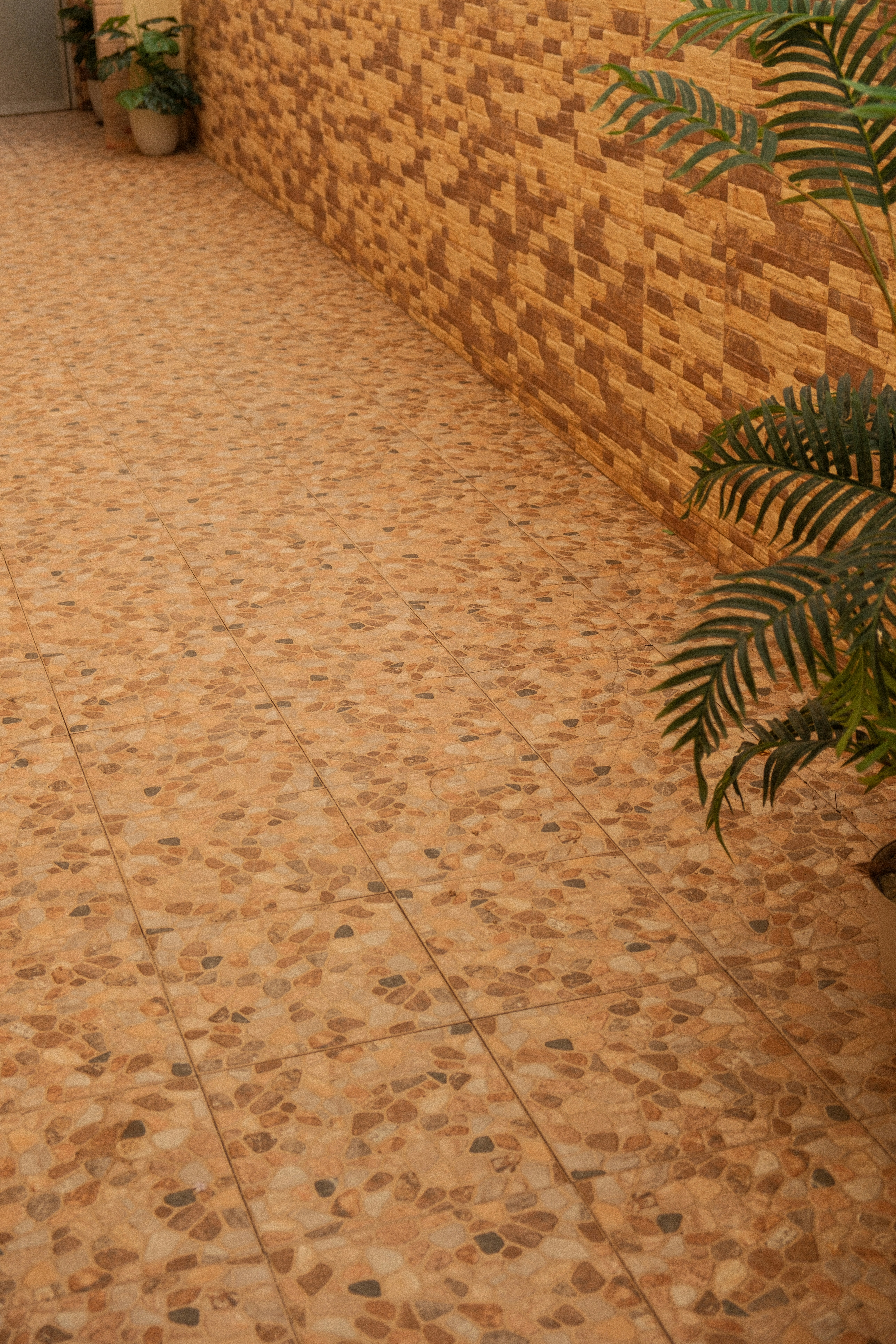 Tiled walkway next to a textured brick wall.