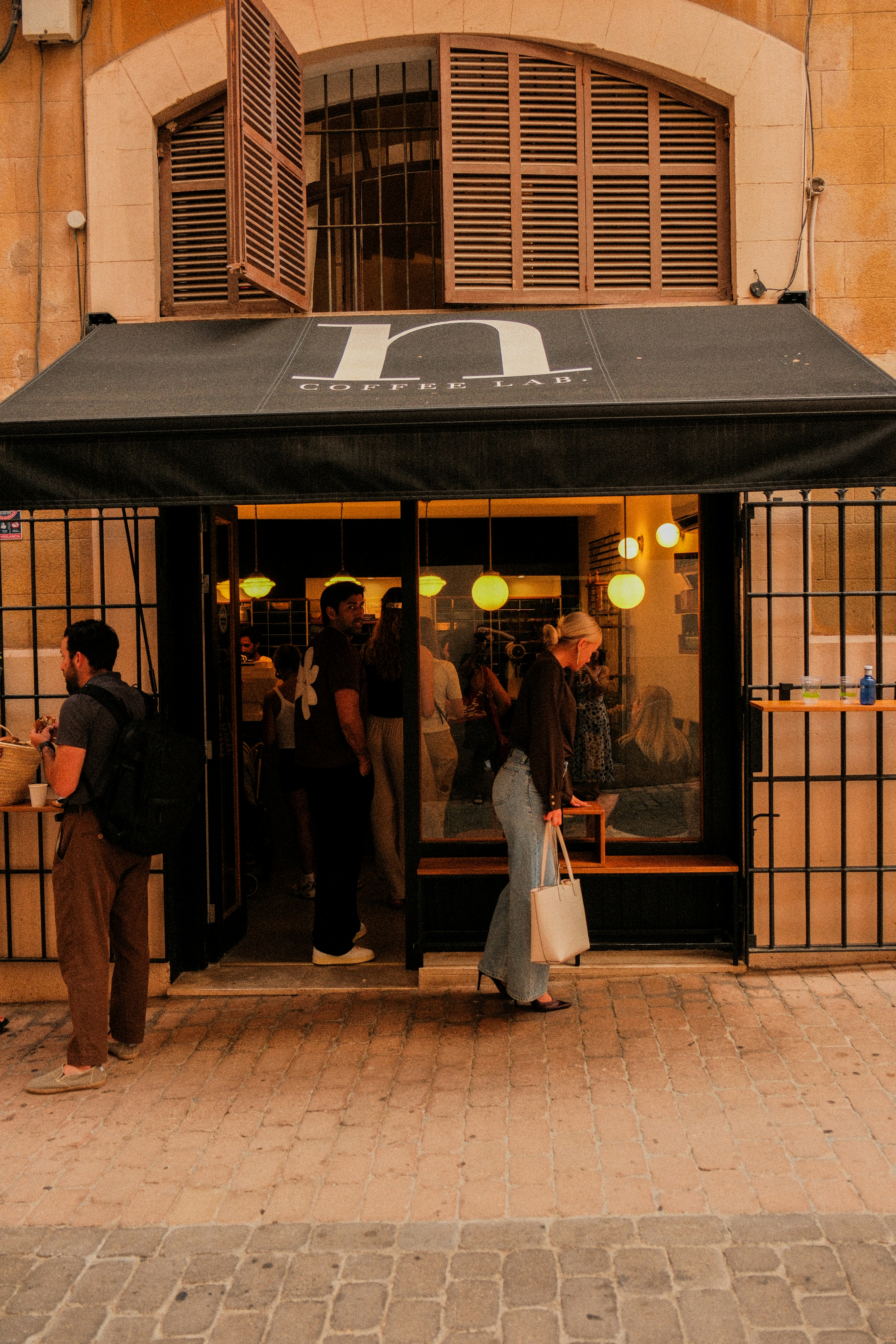 People entering a modern cafe with outdoor seating.