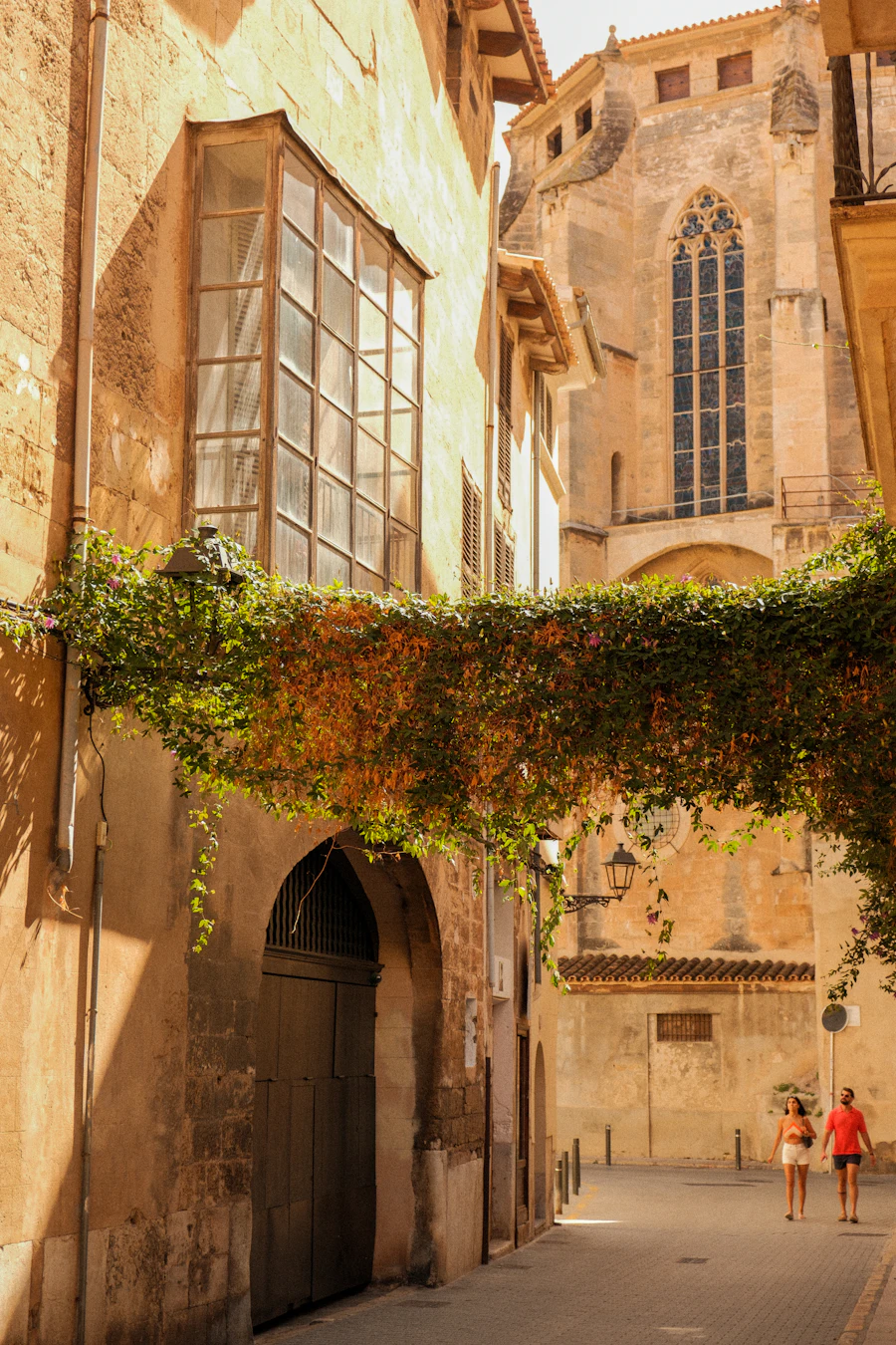 Zwei Menschen gehen durch eine sonnige Altstadtgasse in Spanien