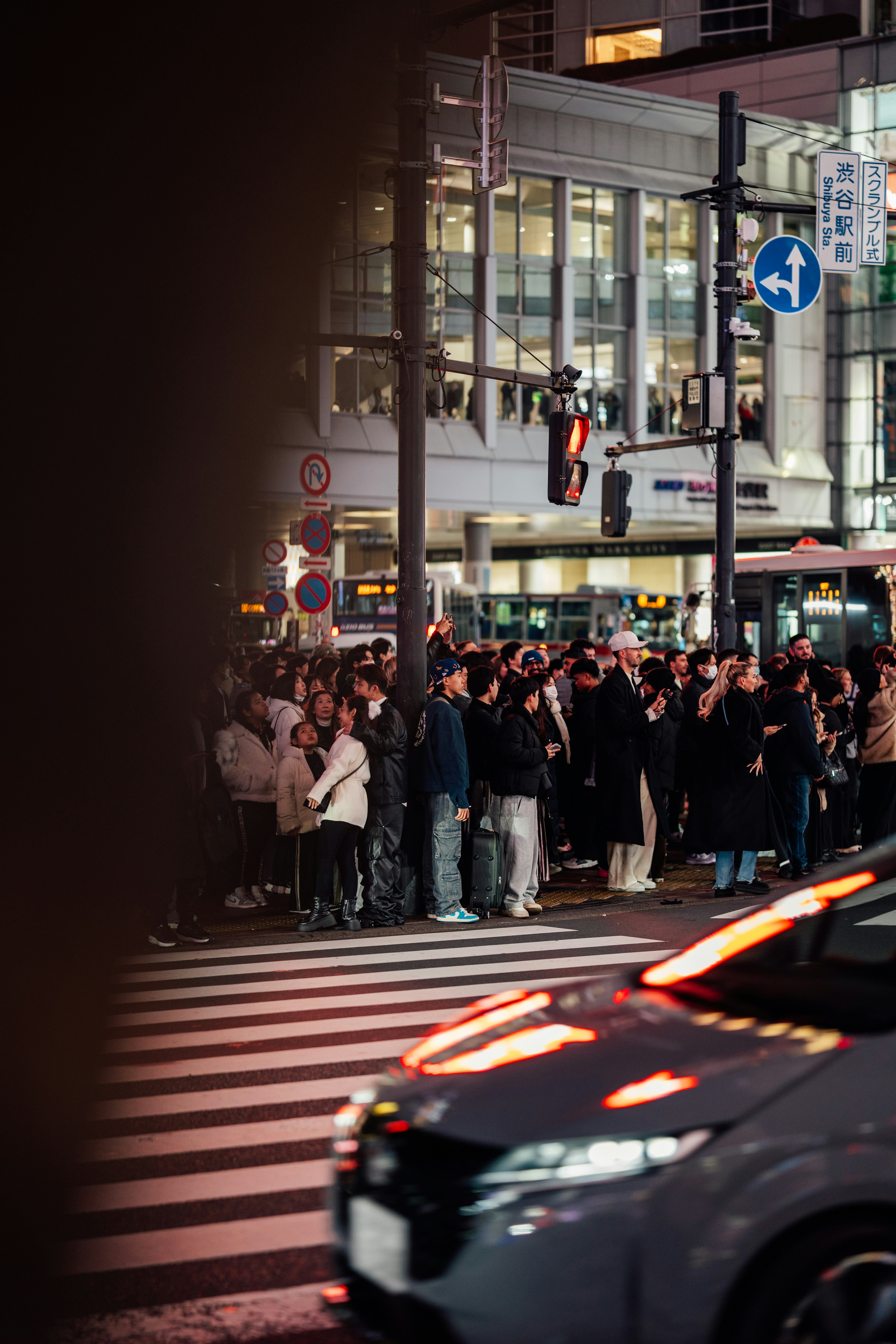 Crowd waiting at a busy city street crossing at night