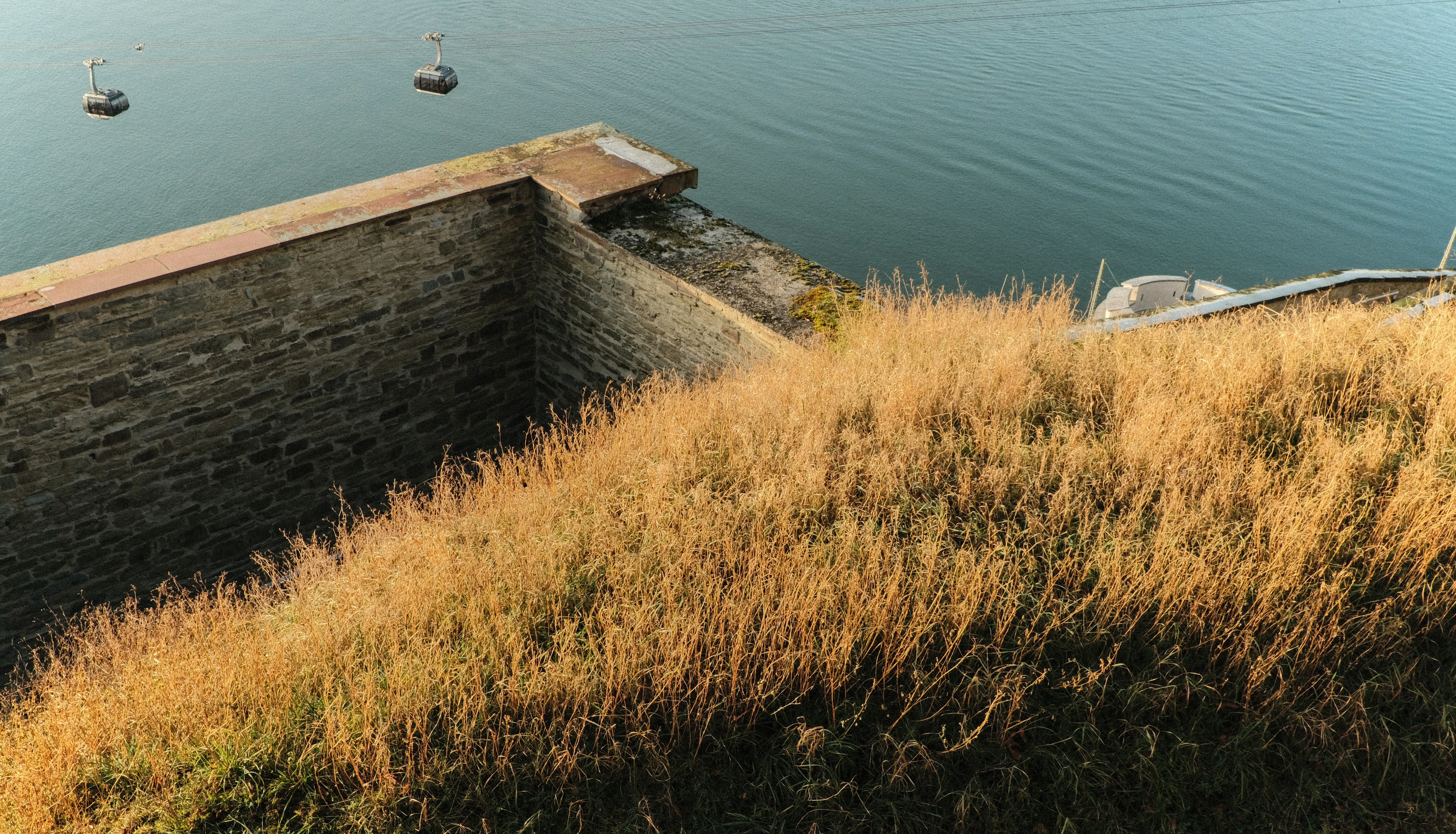 Dry grass on a stone embankment overlooking water