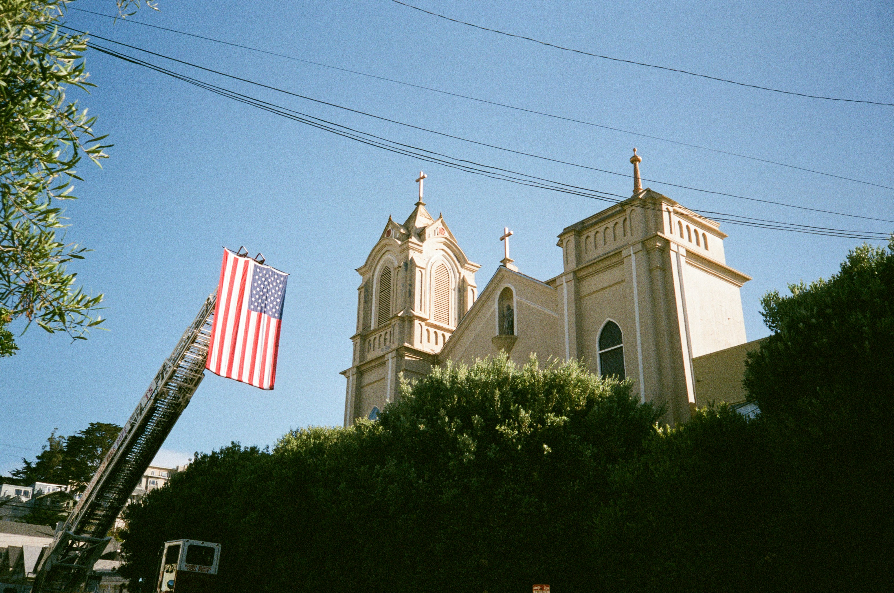 Fire truck ladder with american flag near church