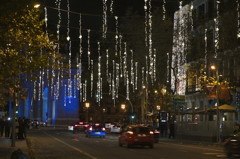 Fotografie: o stradă decorată cu lumini suspendate, noaptea