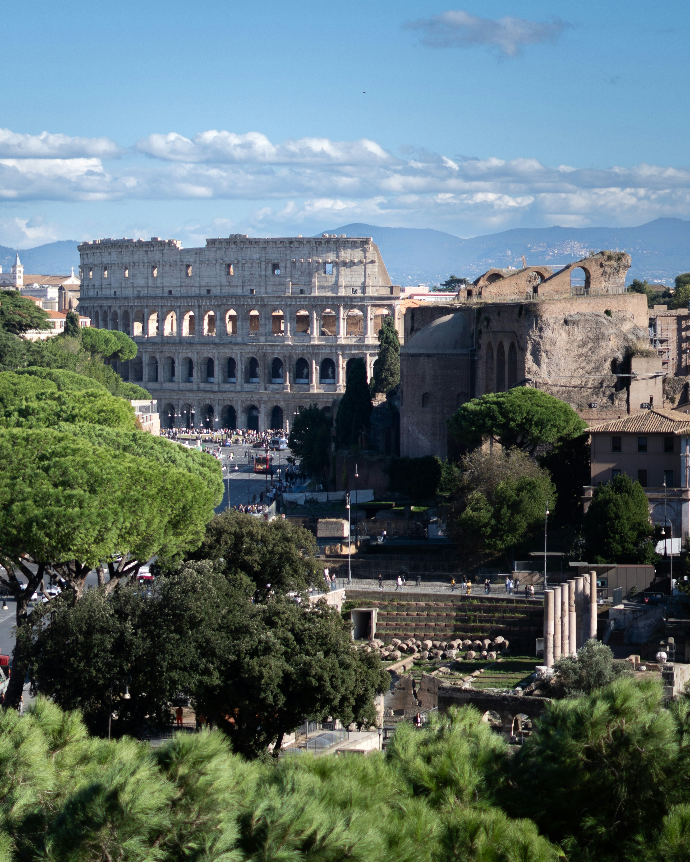 The ancient colosseum in rome with green trees.