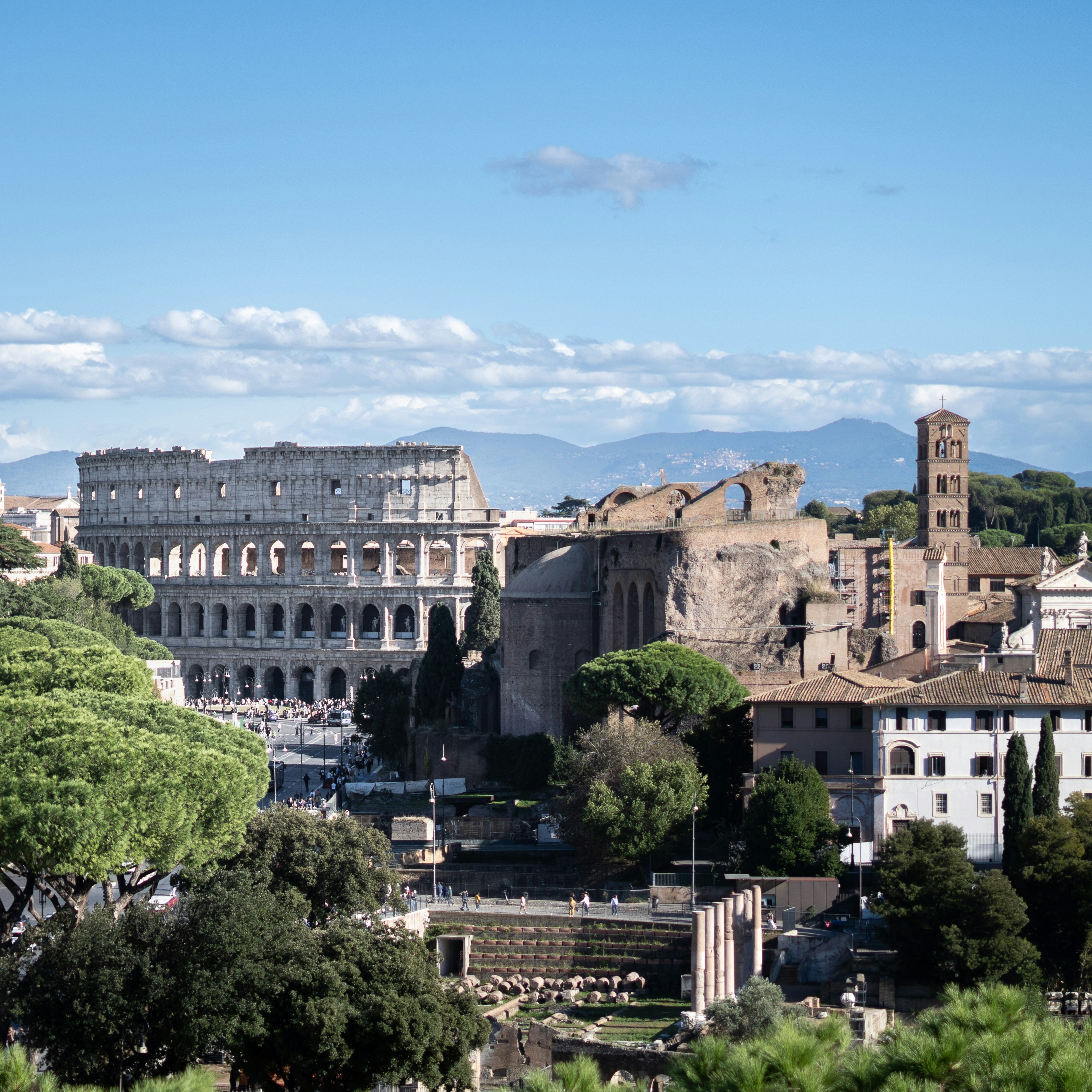 Colosseum and roman forum ruins under blue sky