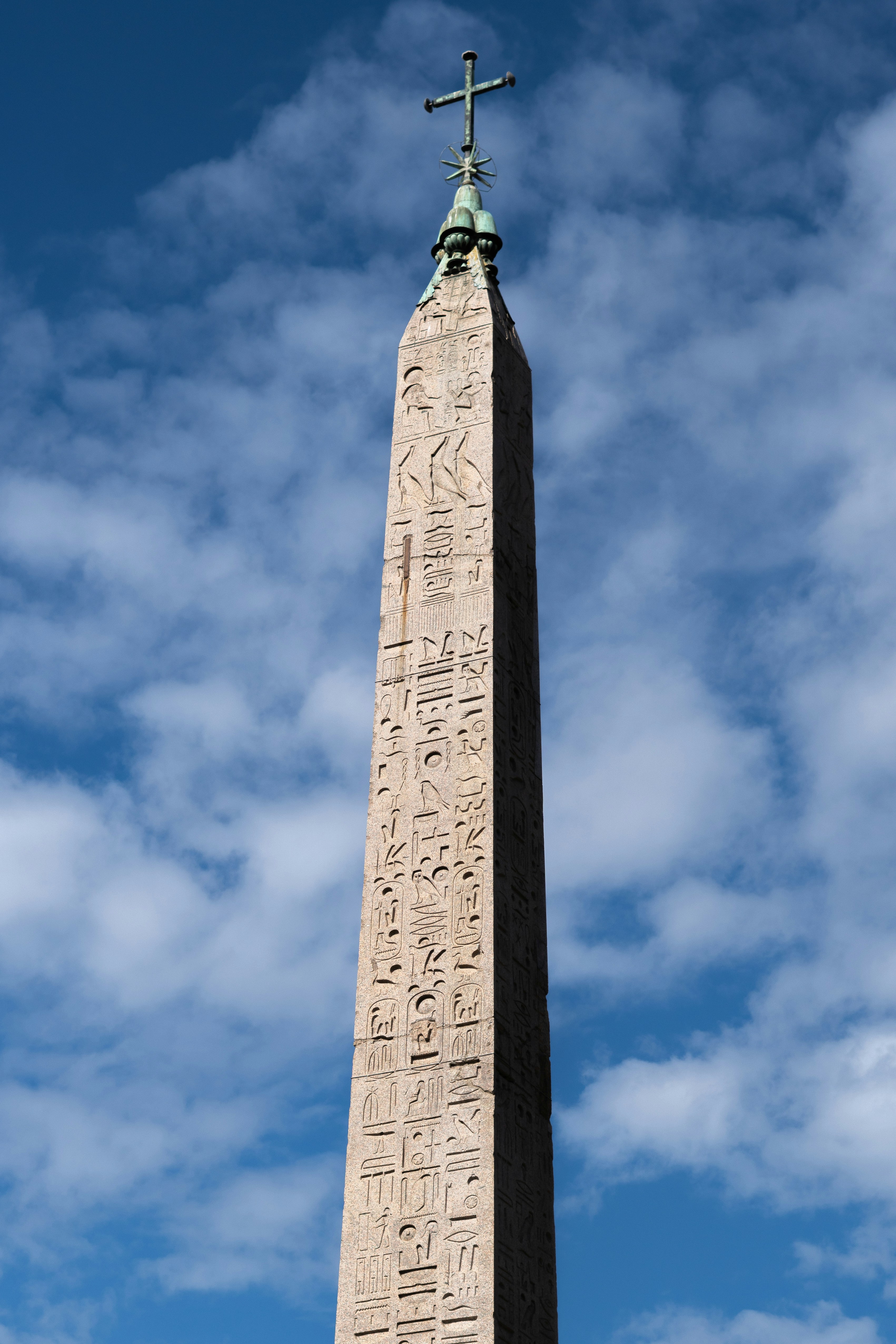 An ancient obelisk with hieroglyphs under a cloudy sky