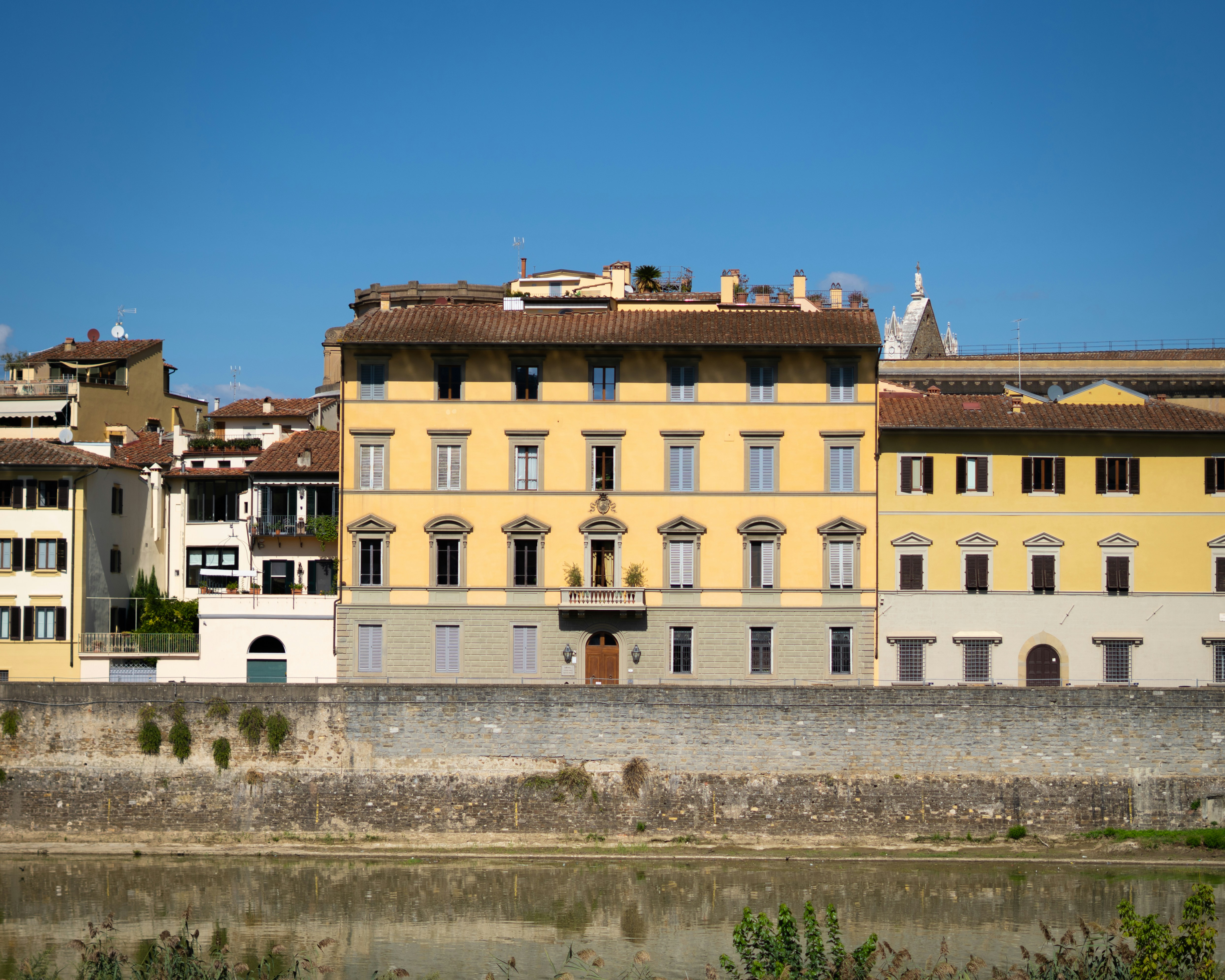 Yellow building facade with windows and rooftops.