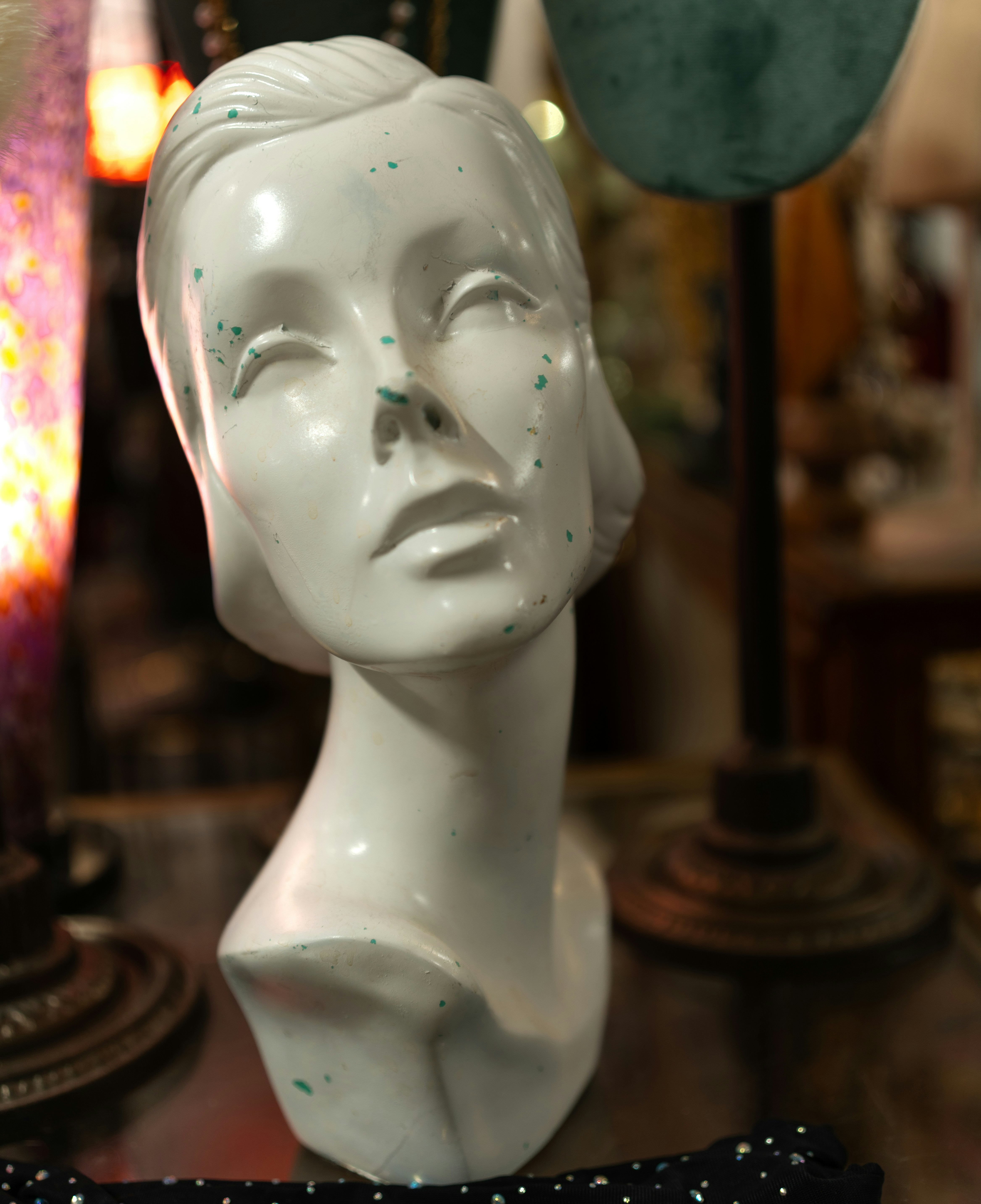 White mannequin head with green speckles