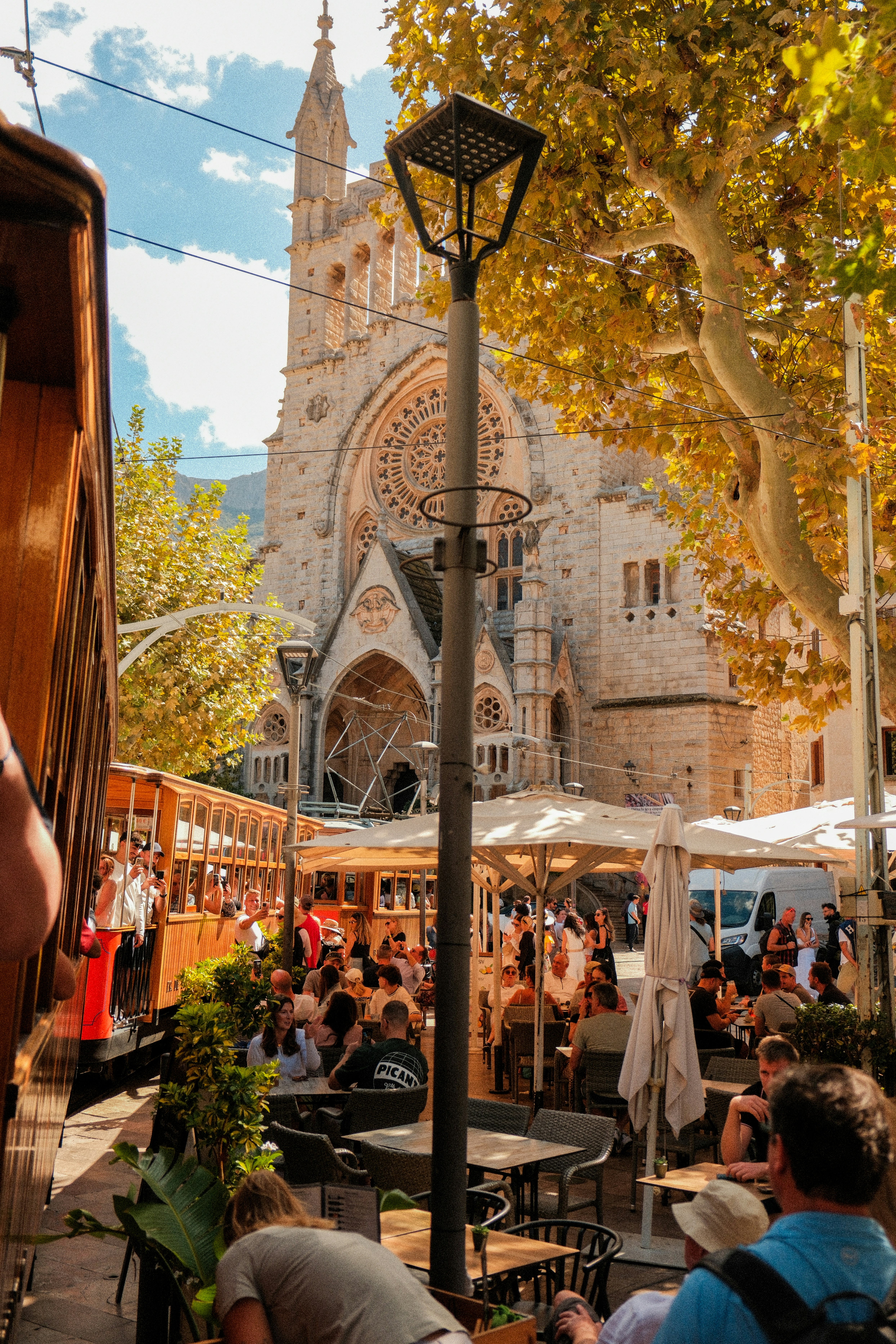 Le vieux tramway passe devant un café avec une grande église derrière