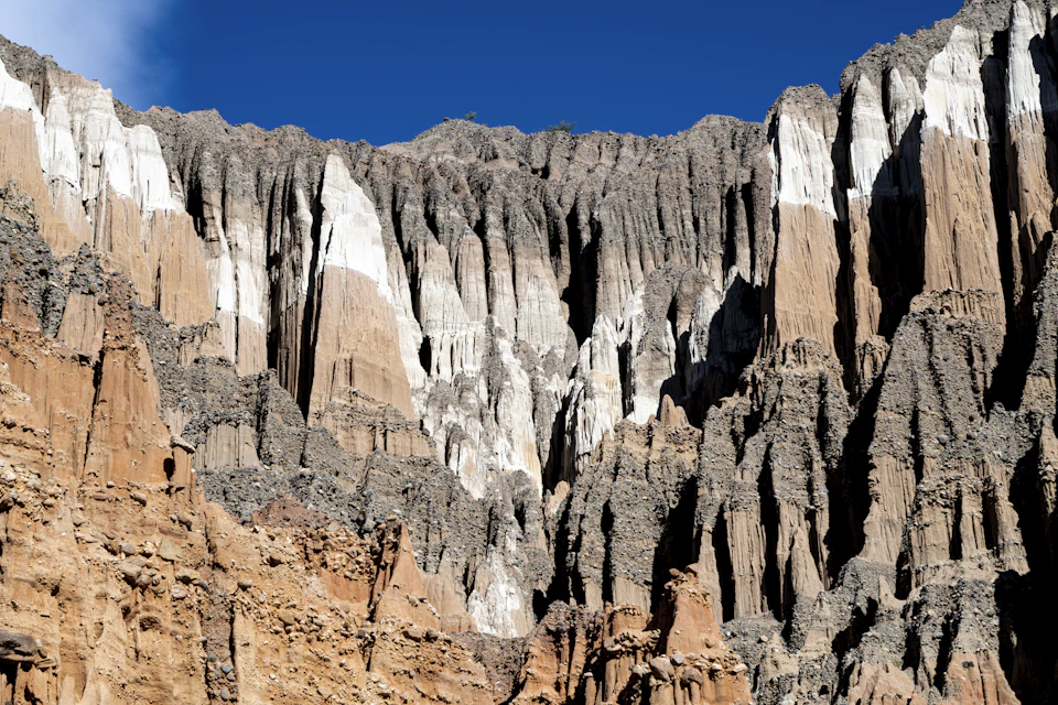 Rugged rocky cliff face with jagged peaks and valleys in brown and gray tones