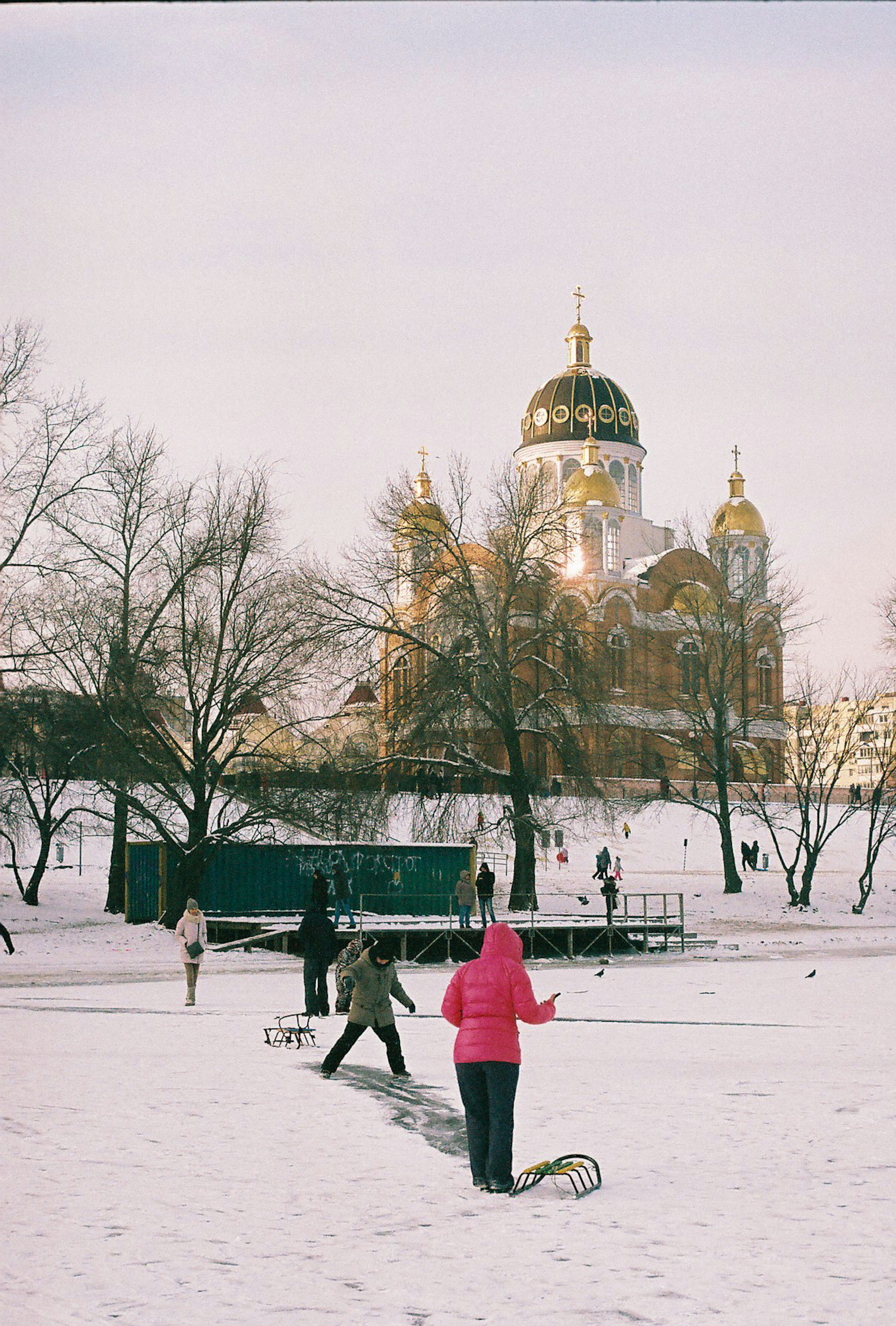 Leute im verschneiten Park mit einem kuppelförmigen Gebäude dahinter.