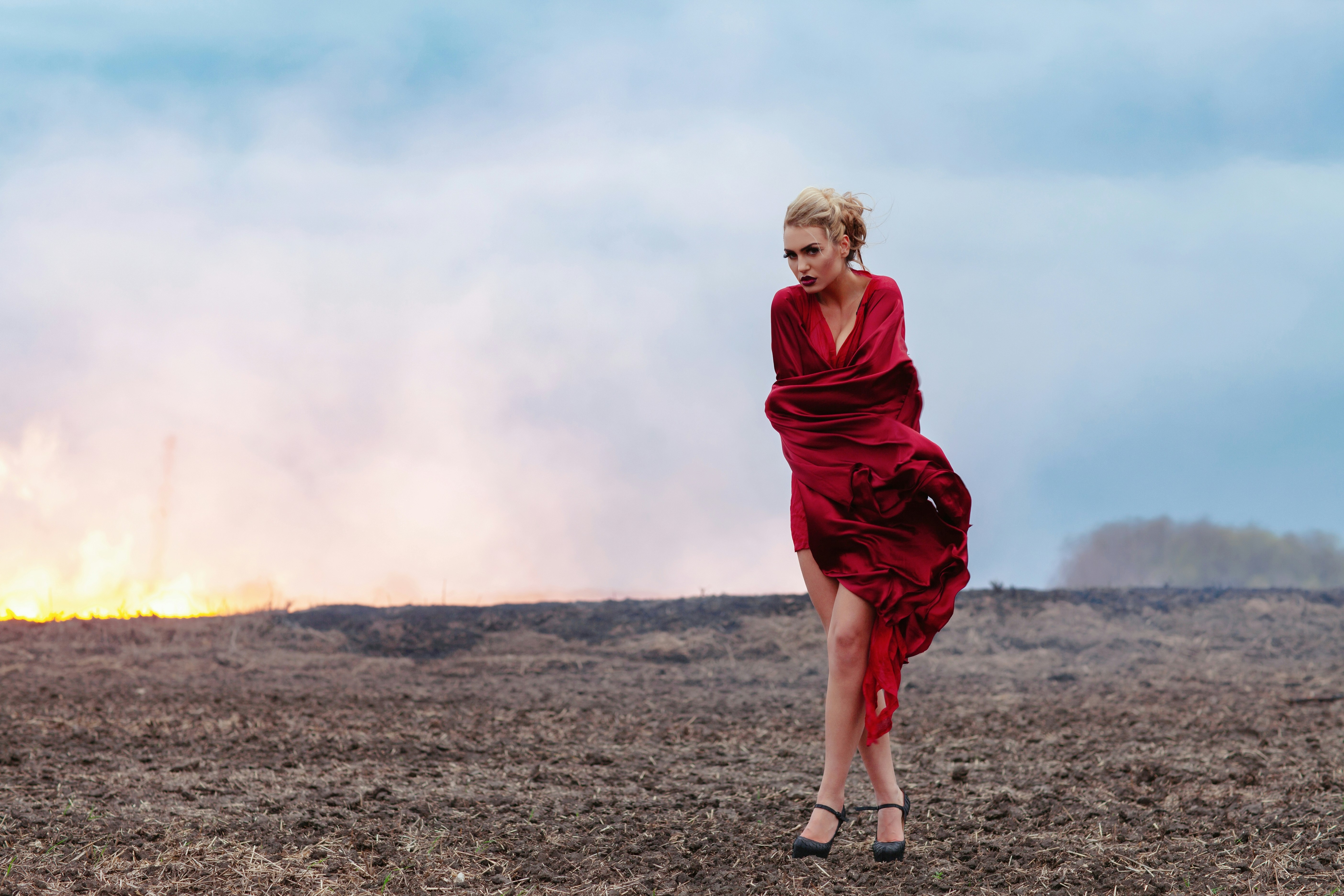 Woman in red dress stands in smoky field
