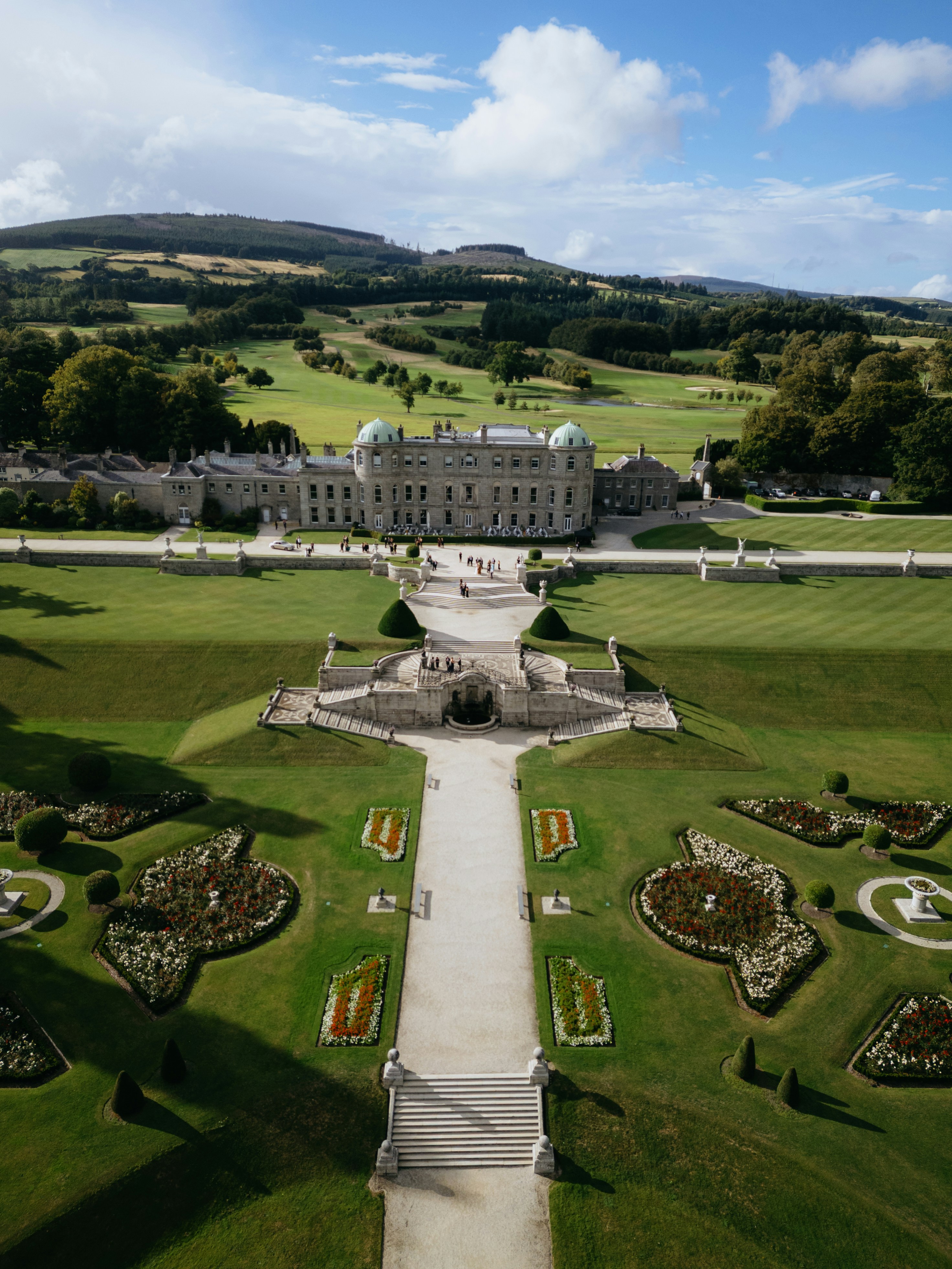 Grand estate with manicured gardens and rolling hills