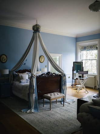 A bedroom with a four-poster bed and blue walls.