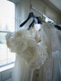 White floral bouquet hangs near wedding dresses