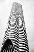 Modern skyscraper with curved balconies against a cloudy sky.