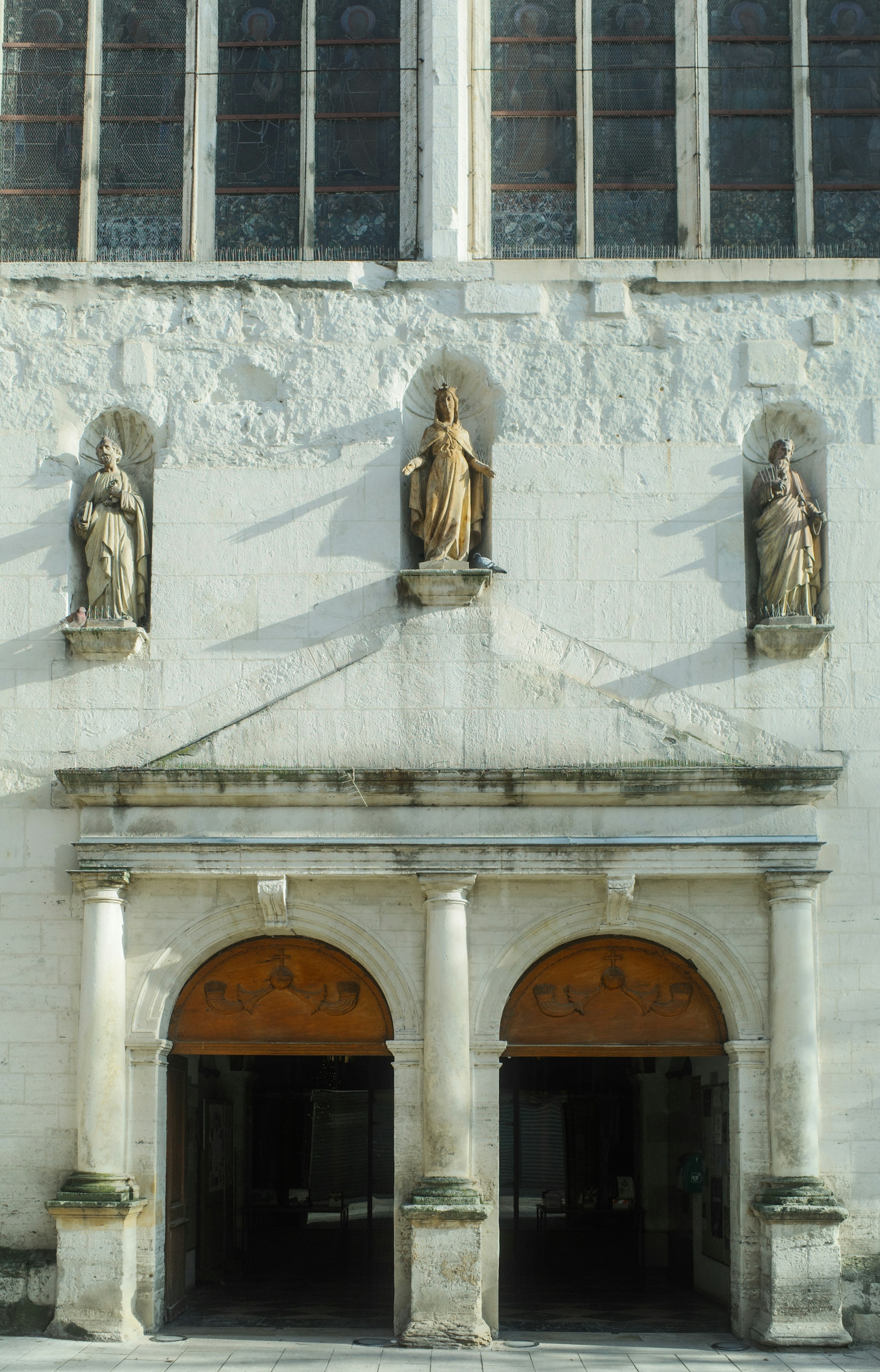 Ornate entrance to a historic building with statues and windows.