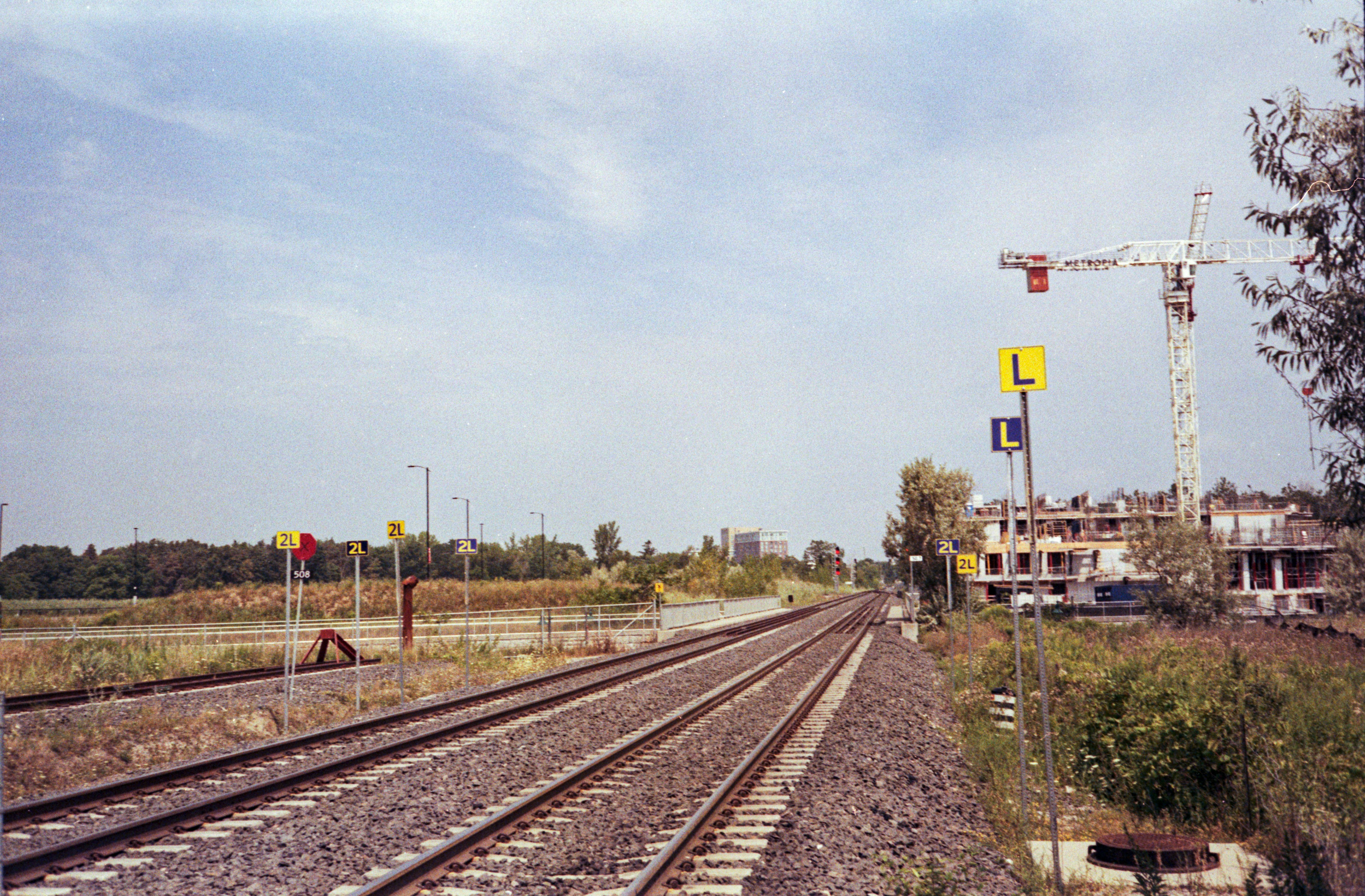Train tracks lead towards a construction site with crane.