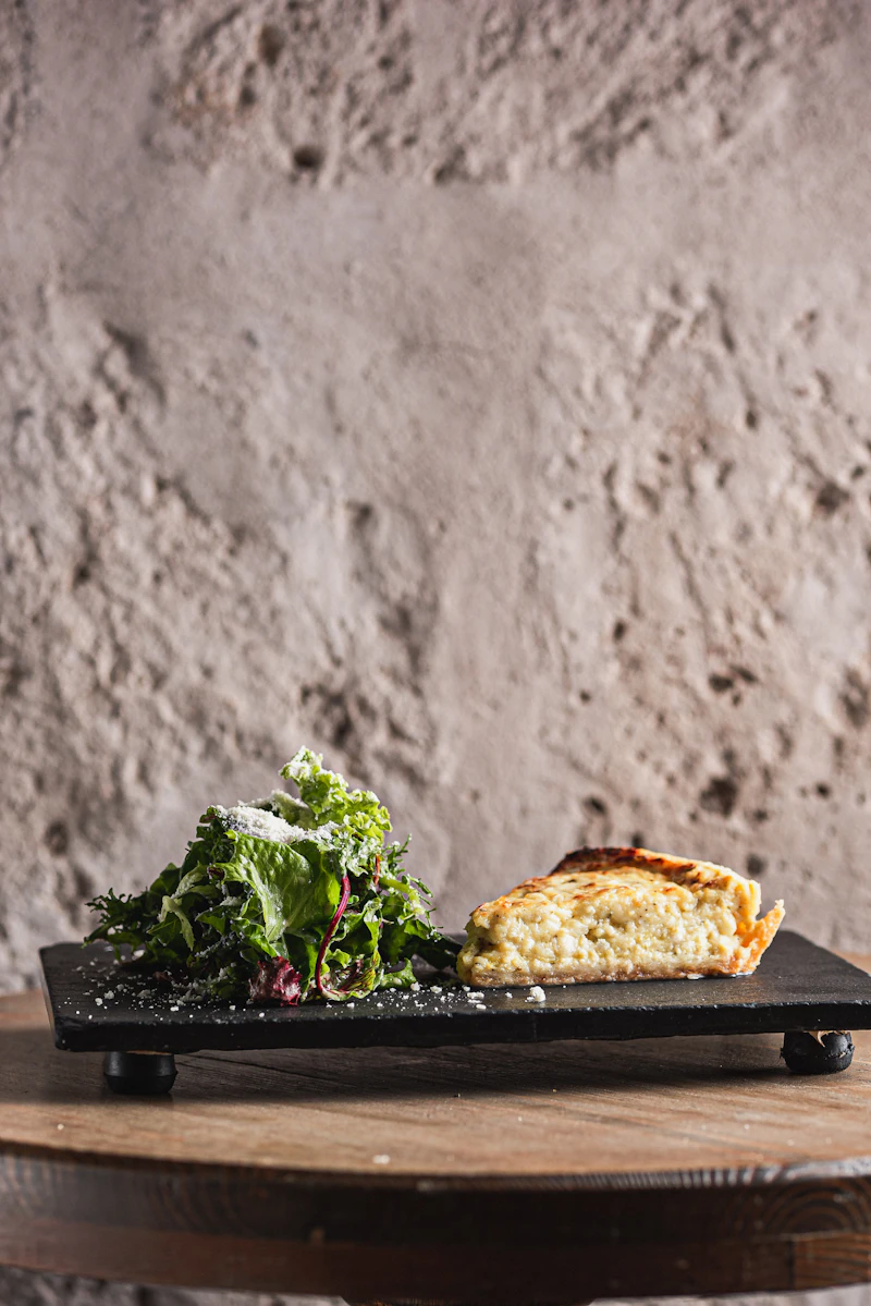 Slice of savoury onion tart with a side salad