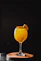 A bright orange cocktail with fruit garnish