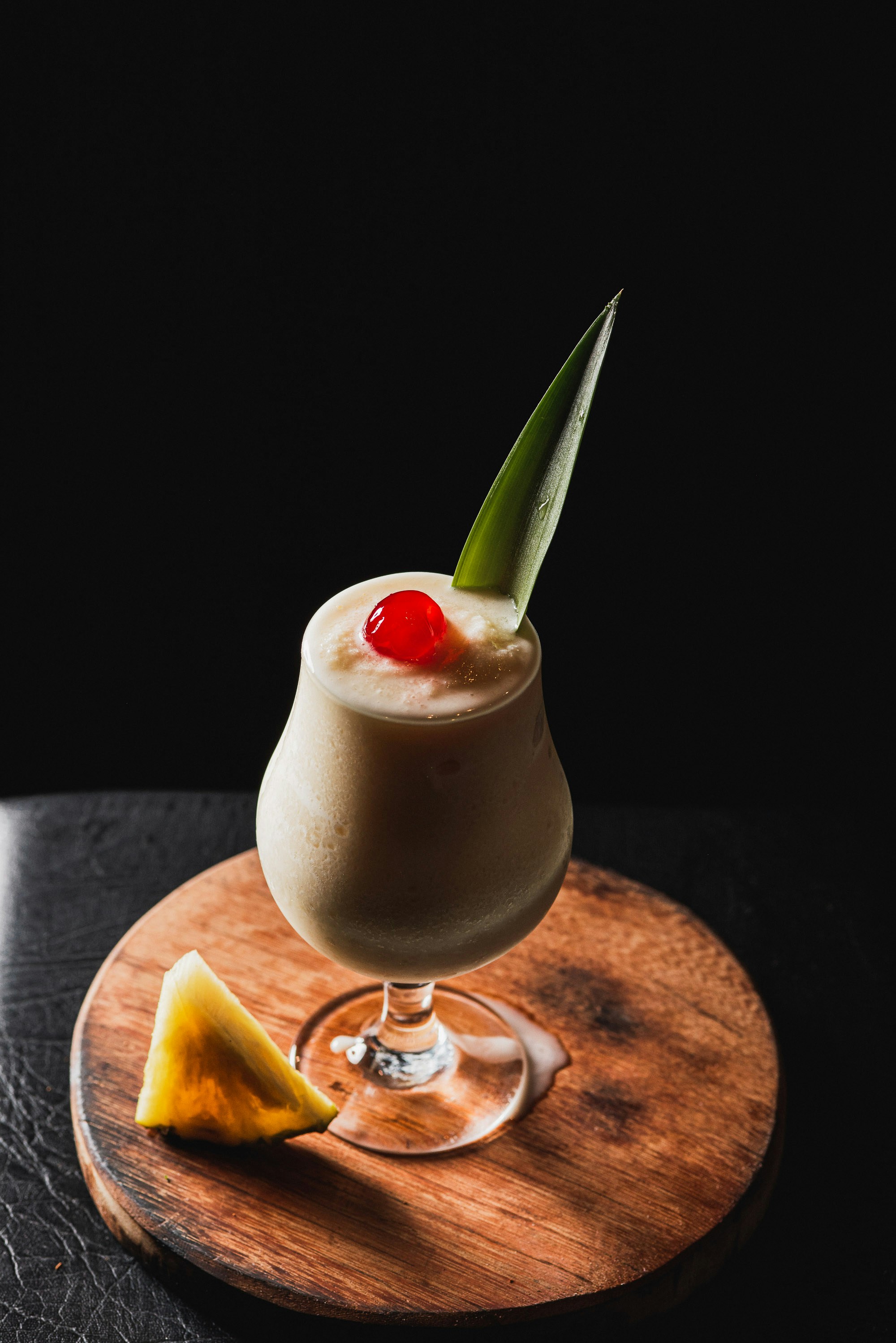 A creamy cocktail with pineapple and cherry garnish